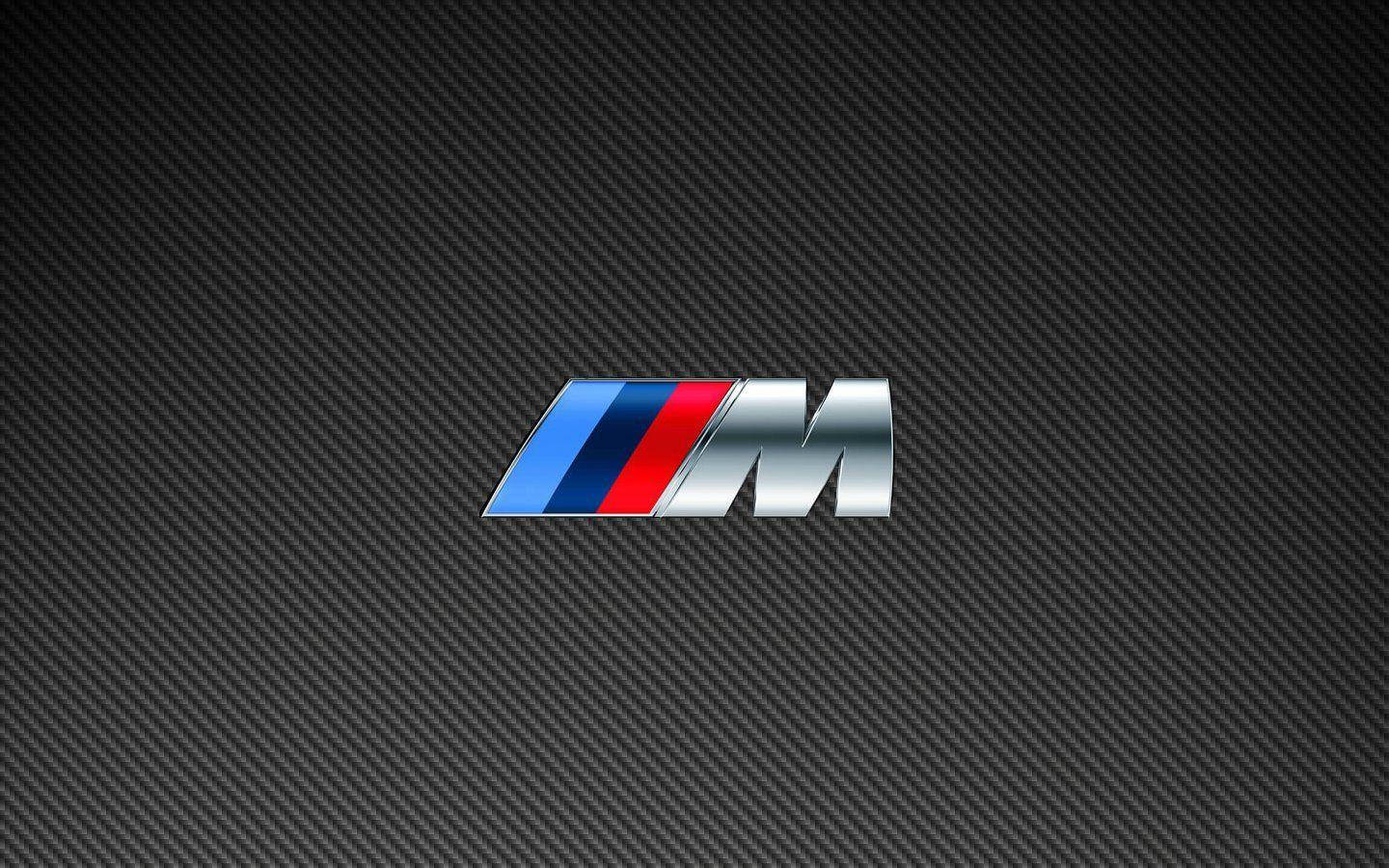 標誌 桌布 壁紙 — 閃亮的BMW M標誌，帶有藍色、紅色和銀色條紋，居中在深色碳纖維紋理背景上。
