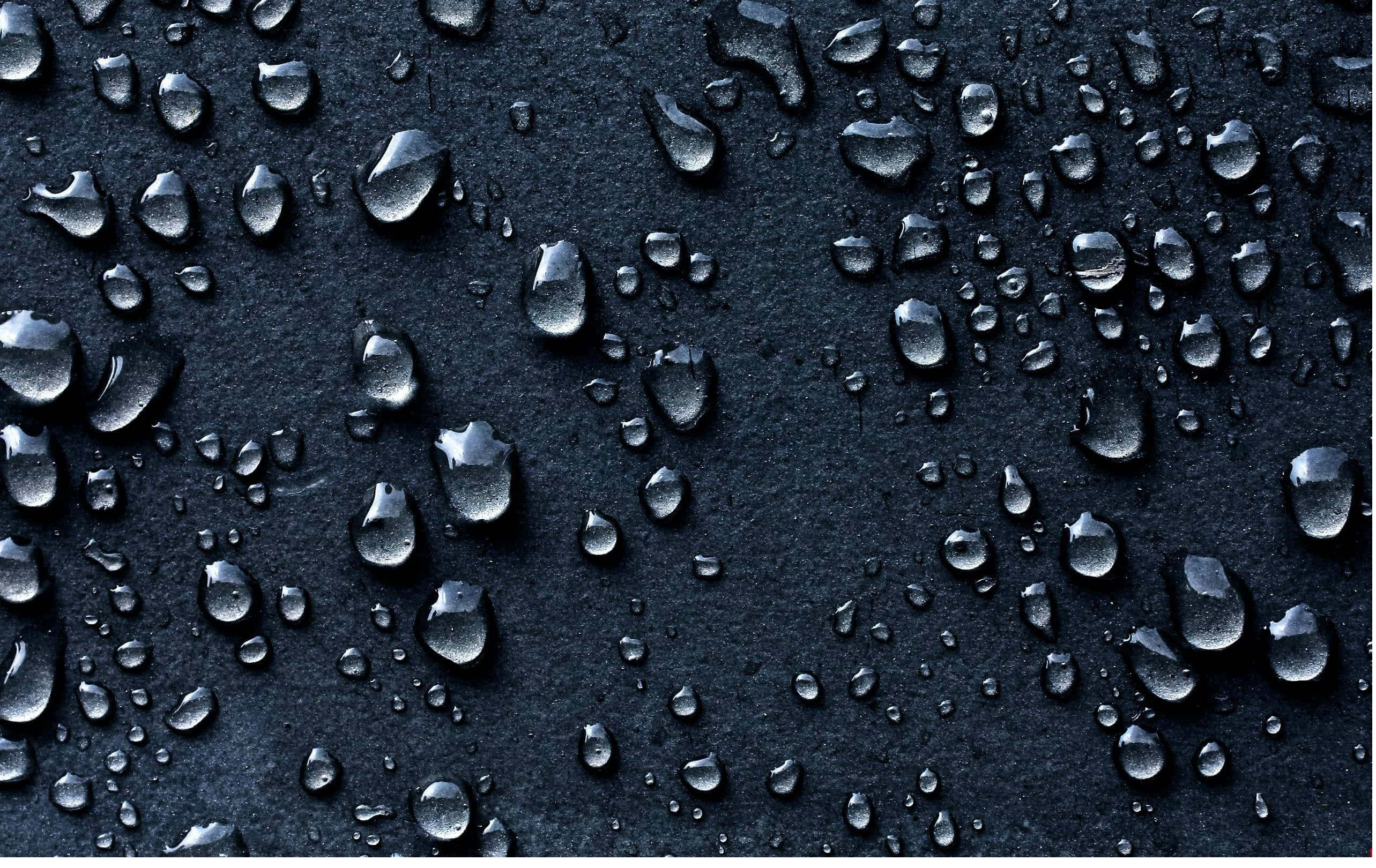 Raining 桌布 壁紙 — 閃亮的水滴依附在霧面黑色紋理表面上，反射柔和的環境光。