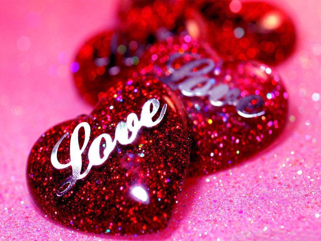 Love Heart 桌布 壁紙 — 閃亮的紅色亮片心形，帶有銀色 'Love' 字樣，放置在閃爍的粉紅色表面上。