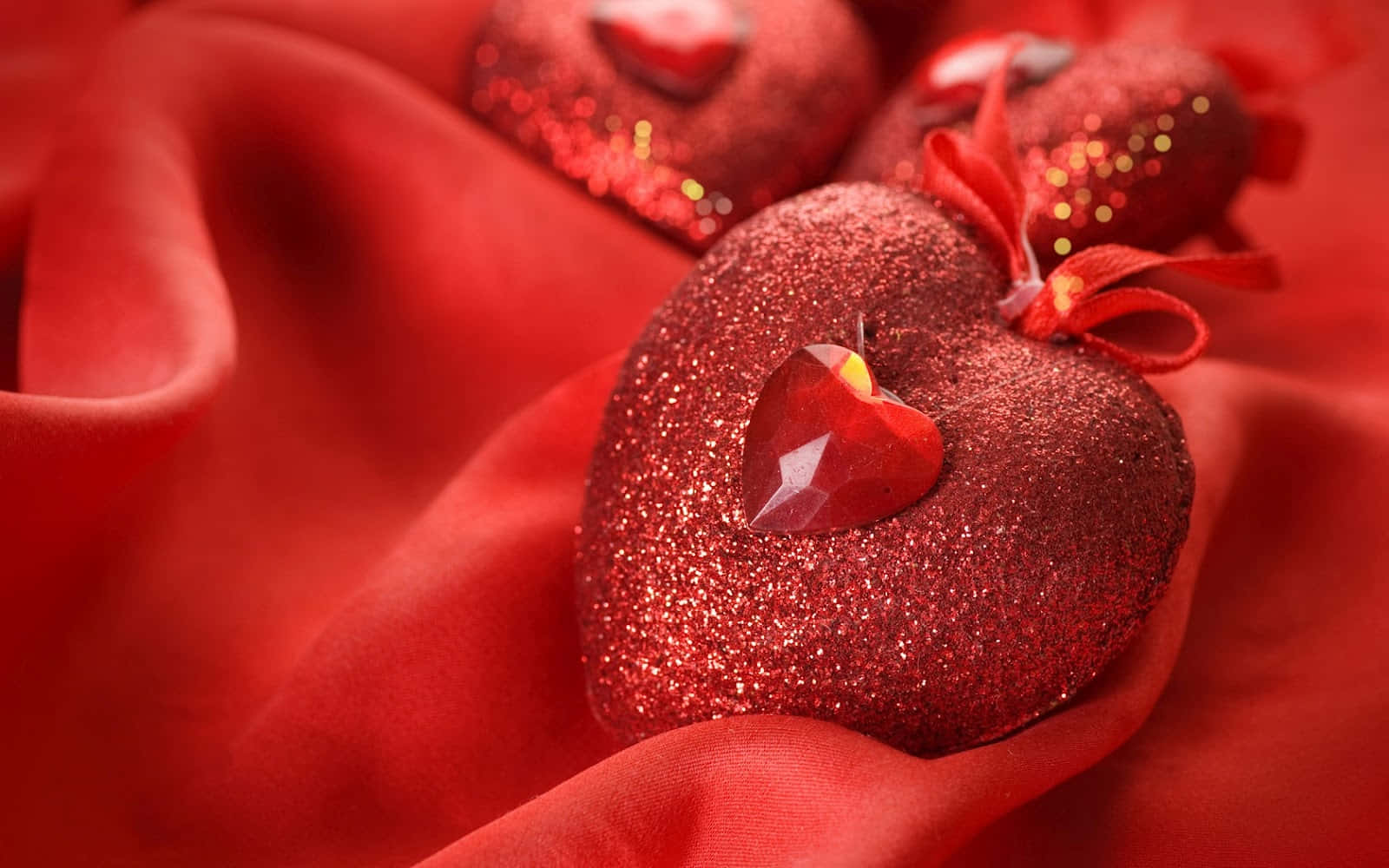 3d Heart 桌布 壁紙 — 閃亮的紅色亮片心形飾以水晶點綴，在特寫鏡頭中放置於豪華的紅色緞面布料上。