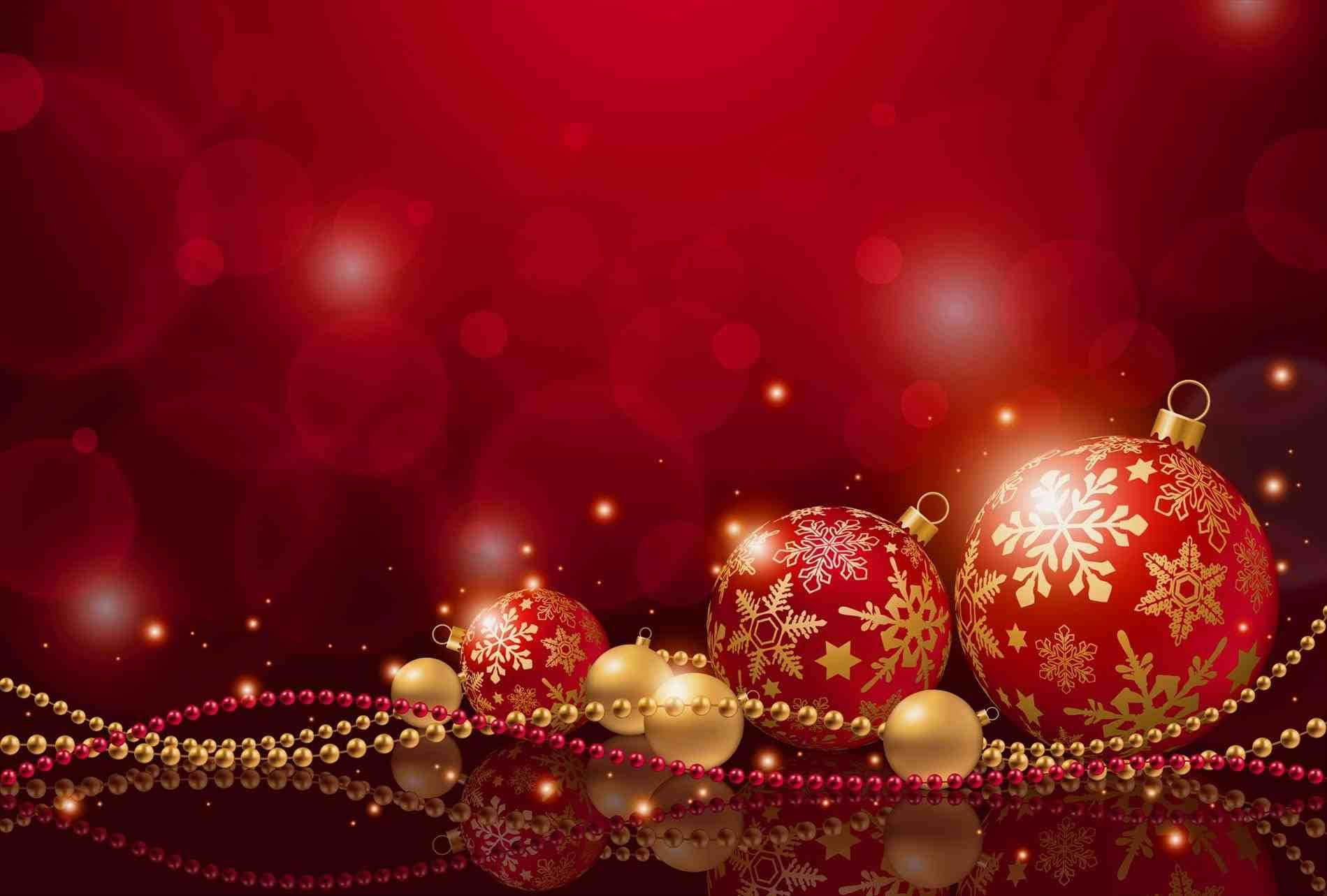 Christmas Red 桌布 壁紙 — 閃亮的紅色和金色聖誕裝飾品帶有雪花圖案，放置在反射表面上，背景是濃郁的紅色散景。
