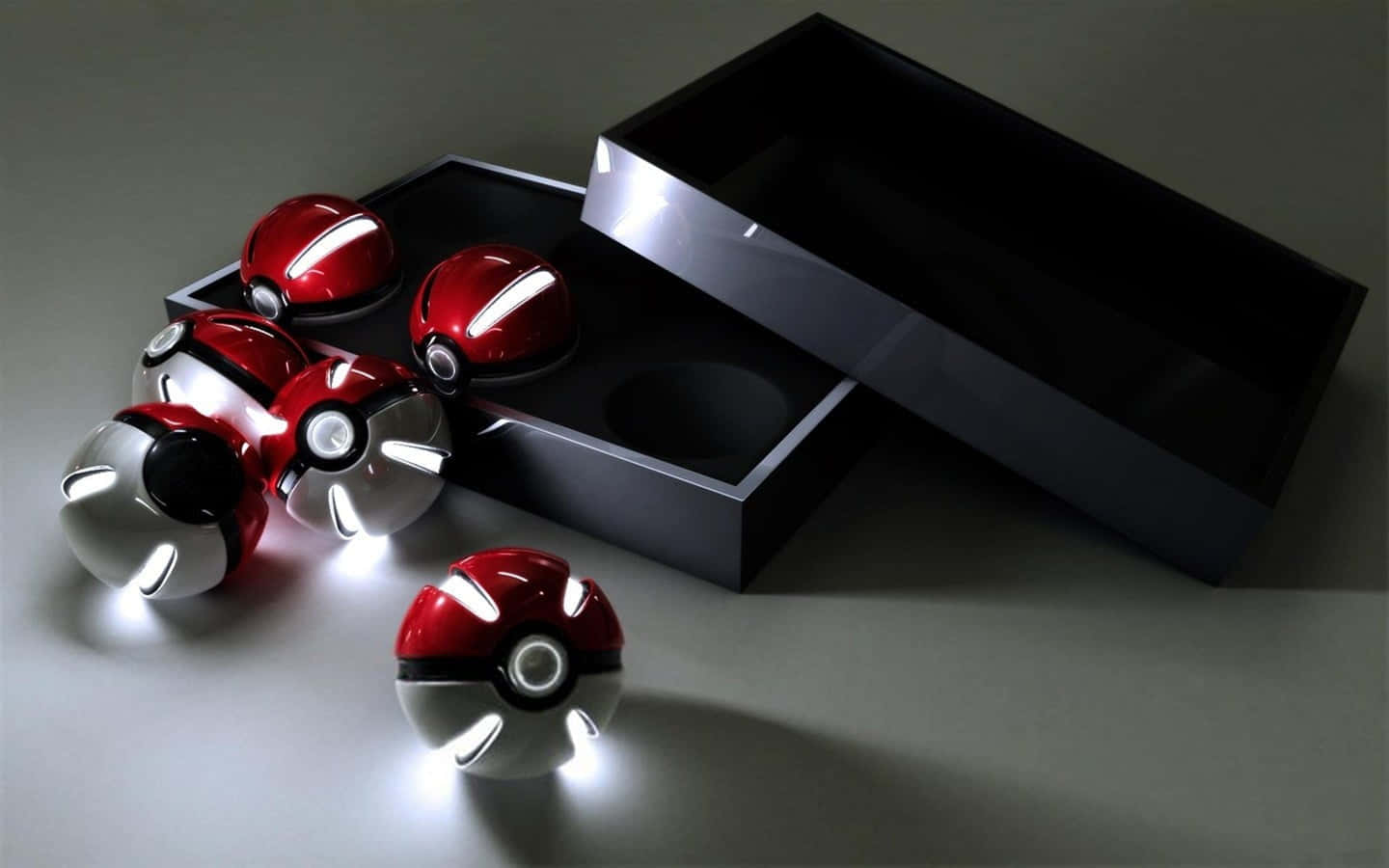 Pokemon Toys 桌布 壁紙 — 閃亮的紅色和銀色寶可夢球帶有發光燈光，從一個時尚的黑色盒子中溢出，放在極簡灰色表面上。