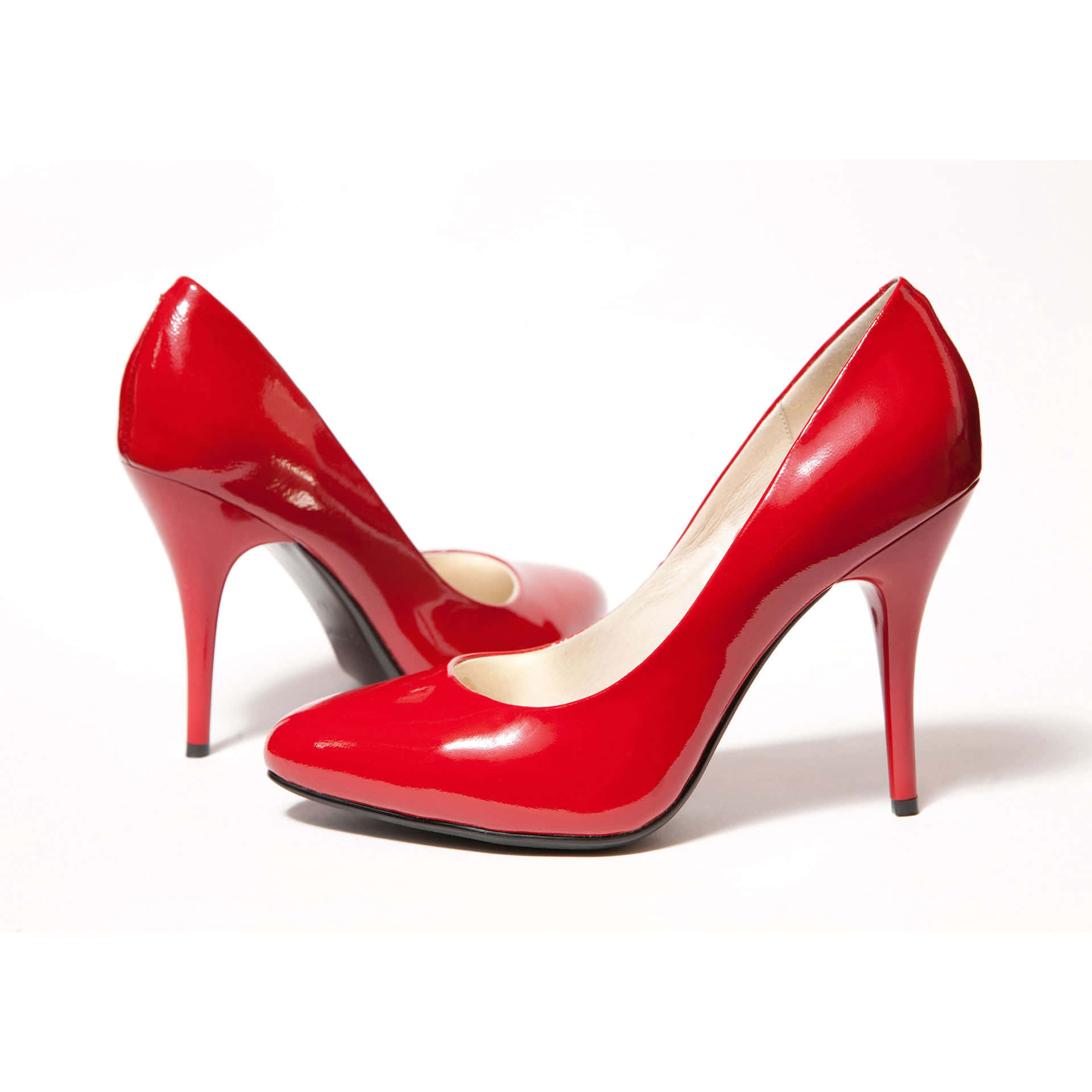 Red High Heels 桌布 壁紙 — 閃亮的紅色漆皮高跟鞋，搭配纖細的細跟和奶油色鞋墊，置於潔淨的白色背景上。