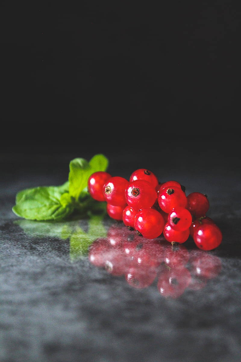 Food Photography 桌布 壁紙 — 閃亮的紅醋栗與新鮮薄荷葉在柔和燈光下放置於深色反光表面上。