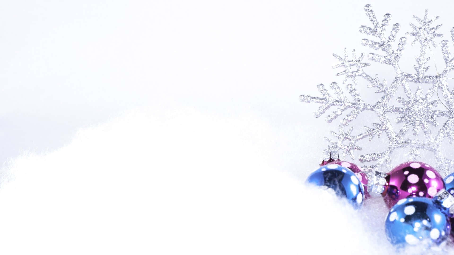 雪 桌布 壁紙 — 閃亮的藍色和紫色聖誕裝飾品依偎在柔軟的白雪中，旁邊是閃閃發光的銀色雪花。