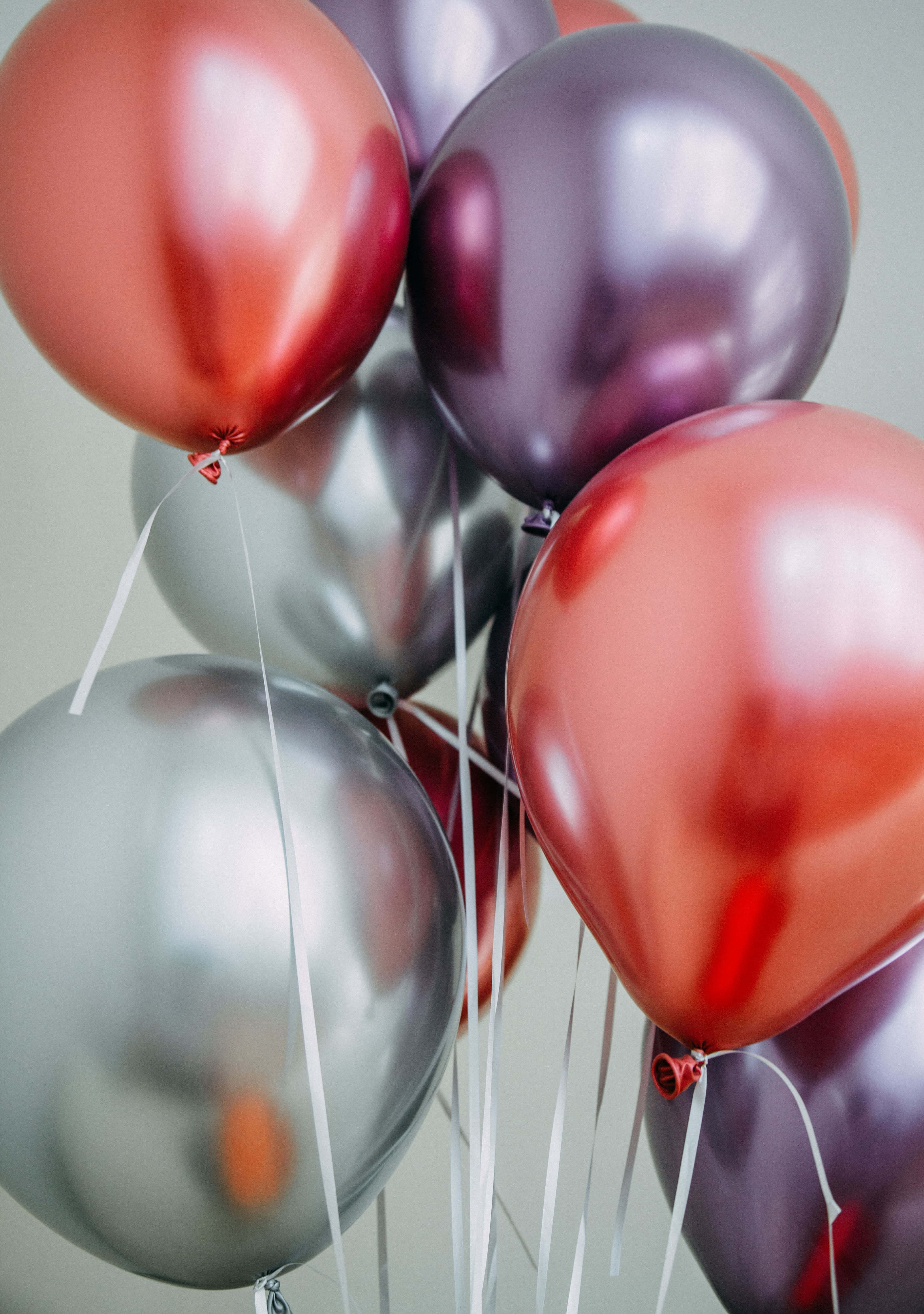 Birthday Balloons 桌布 壁紙 — 閃亮的金屬氣球，玫瑰金色和銀色，在柔和的灰色背景上漂浮，帶有精緻的白色絲帶。