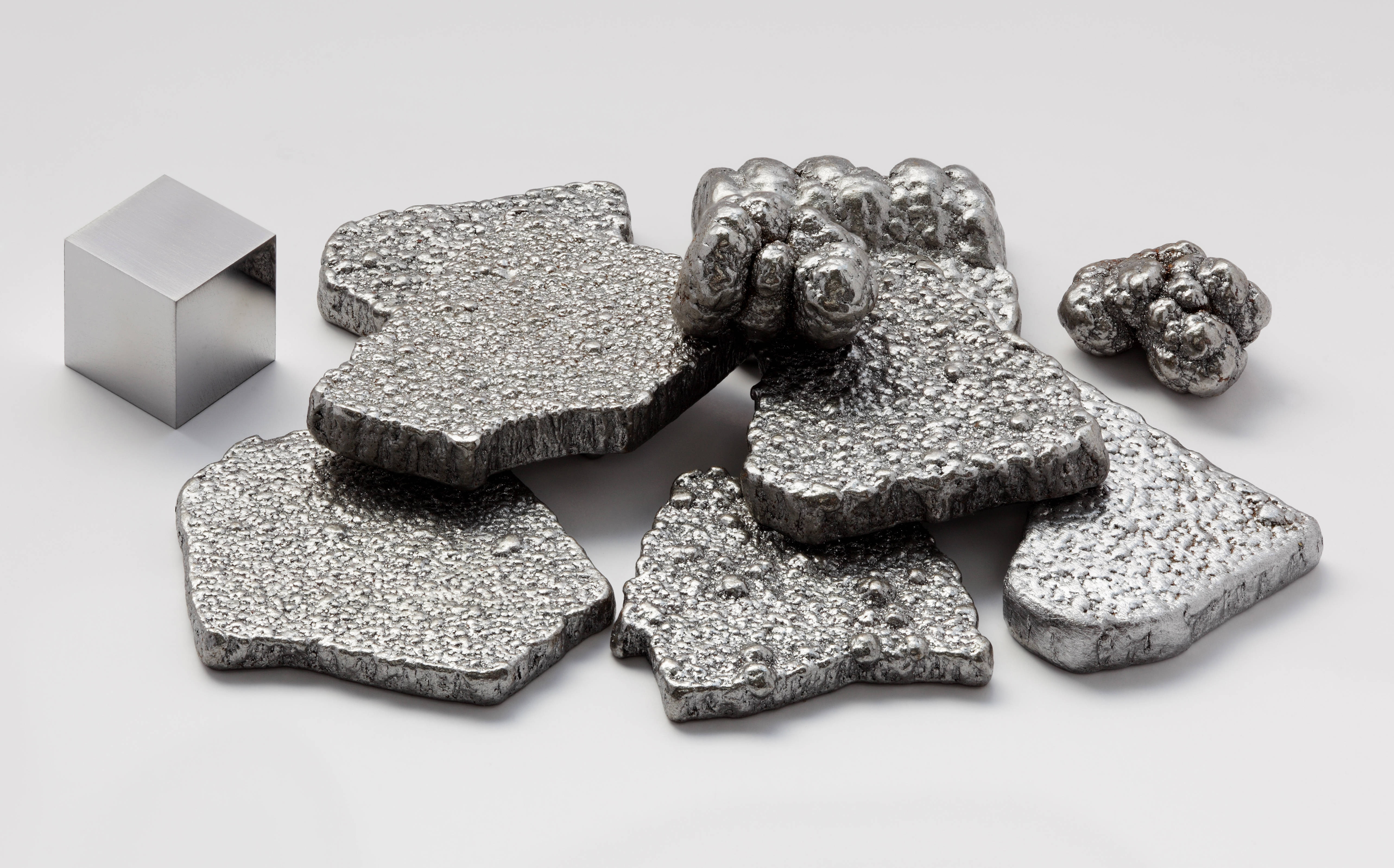 Material 桌布 壁紙 — 閃亮的金屬錠和一個完美的立方體排列在明亮的攝影棚燈光下的純白表面上。