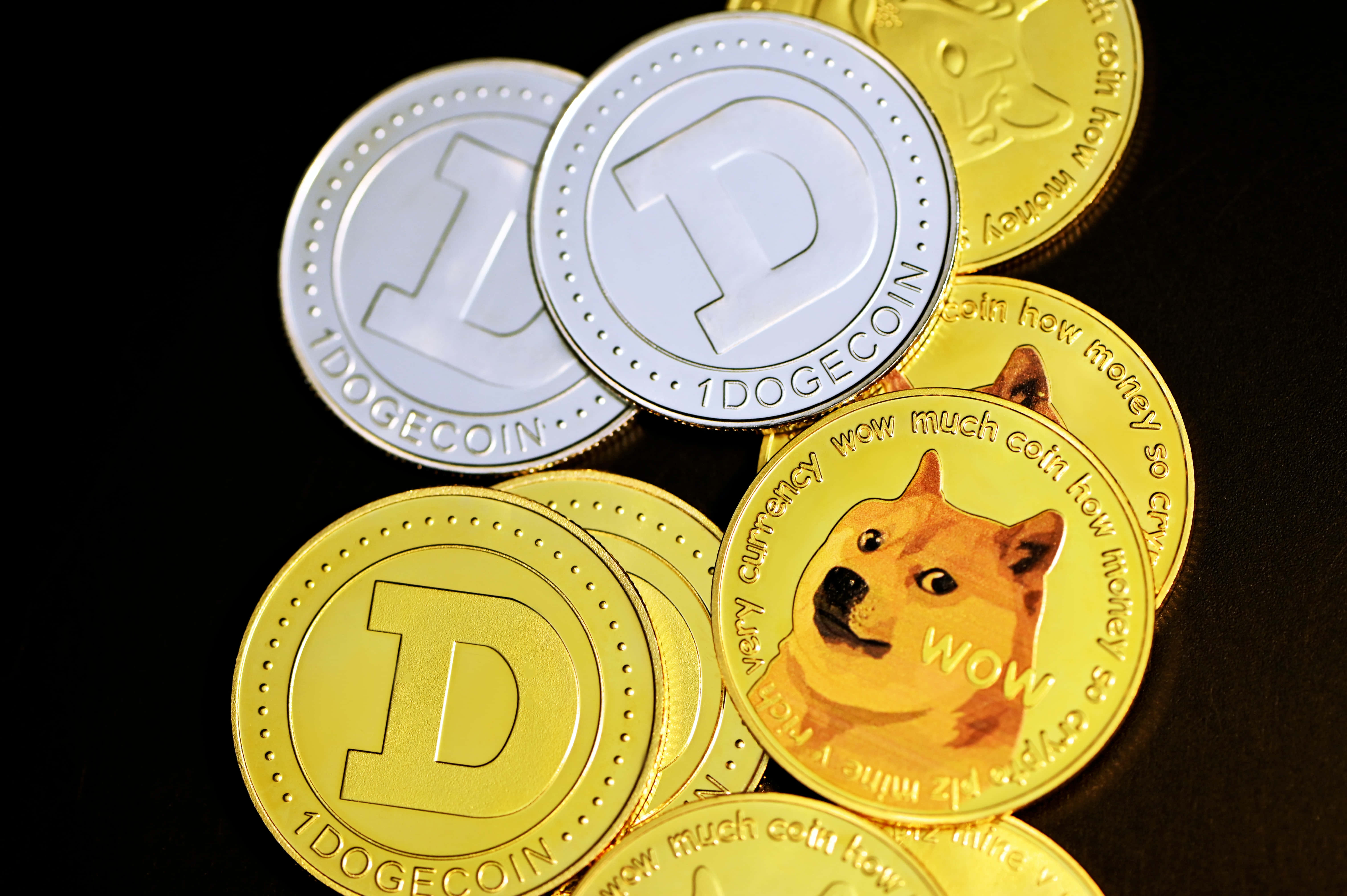 Dogecoin 桌布 壁紙 — 閃亮的金色和銀色狗狗幣代幣，帶有柴犬臉孔，堆疊在黑色背景上。
