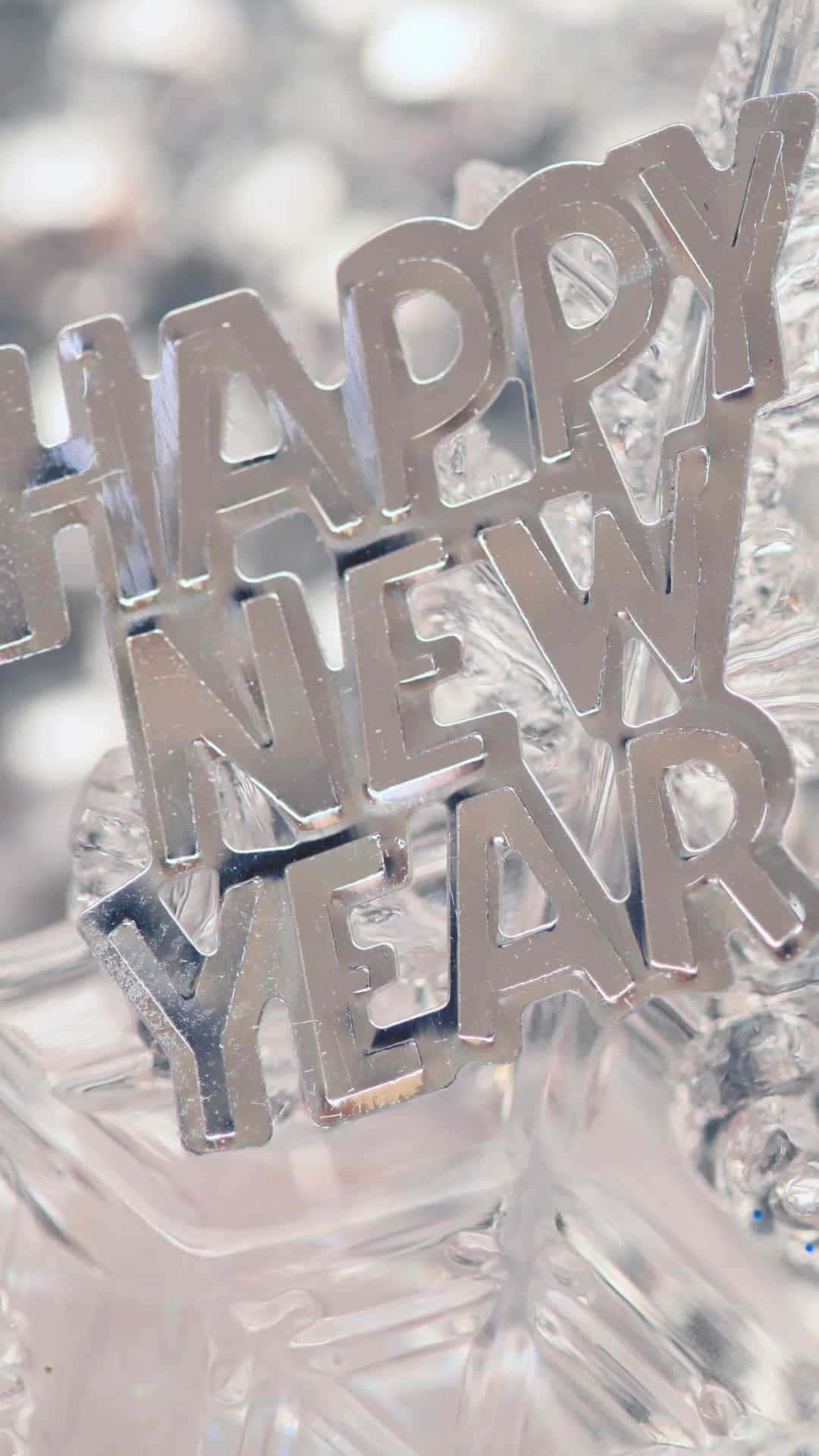 Happy New Year iPhone 桌布 壁紙 — 閃亮的銀色 'HAPPY NEW YEAR' 字母放在閃爍的水晶裝飾上，背景柔和散景。