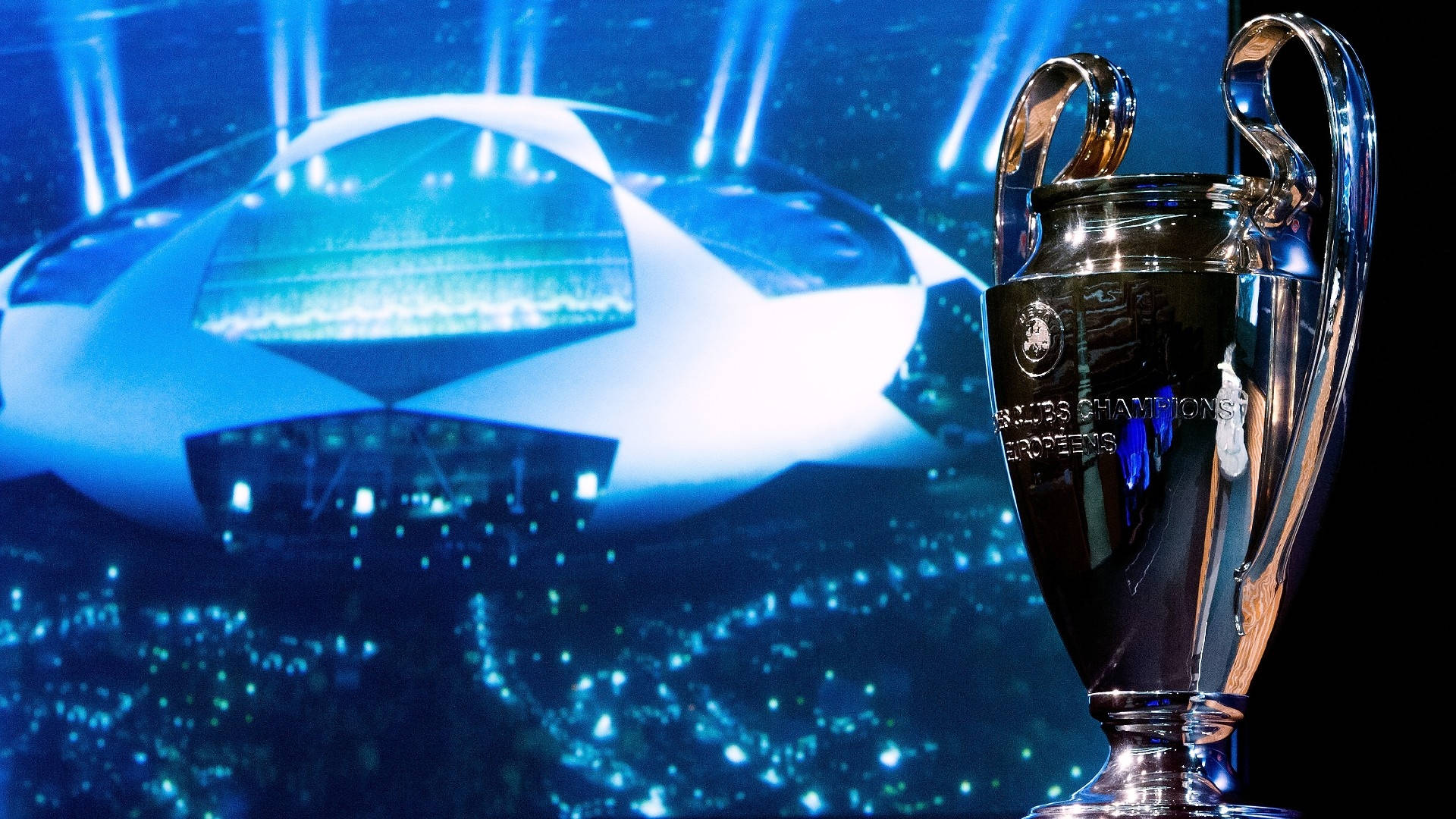 Champions League 桌布 壁紙 — 閃亮的銀色歐冠獎盃在前景閃耀，背景是燈火通明、坐滿球迷的球場。