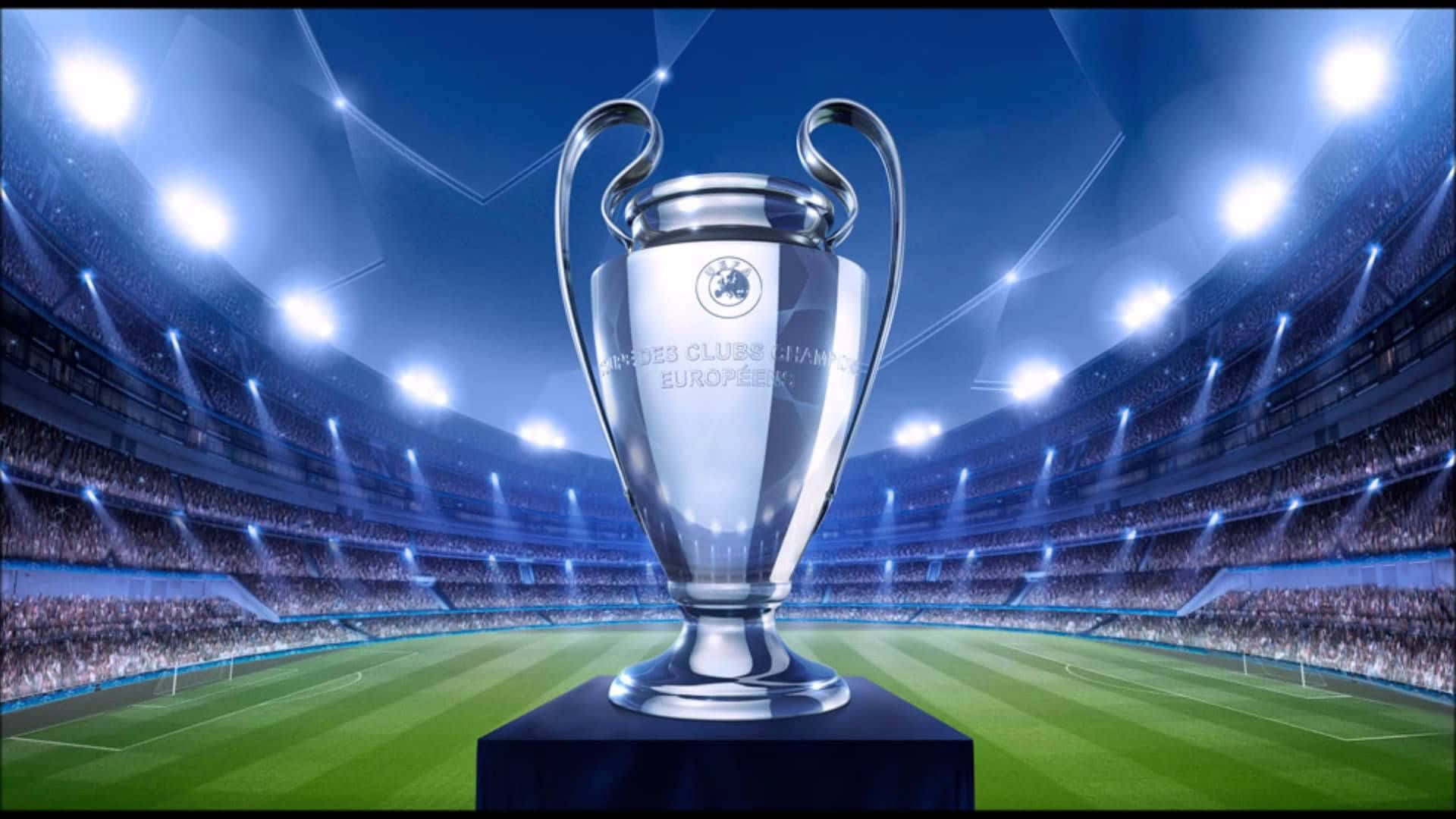 Champions League 桌布 壁紙 — 閃亮的銀色歐洲冠軍聯賽獎盃，在明亮的球場燈光下，位於球場中央，周圍是歡呼的人群。