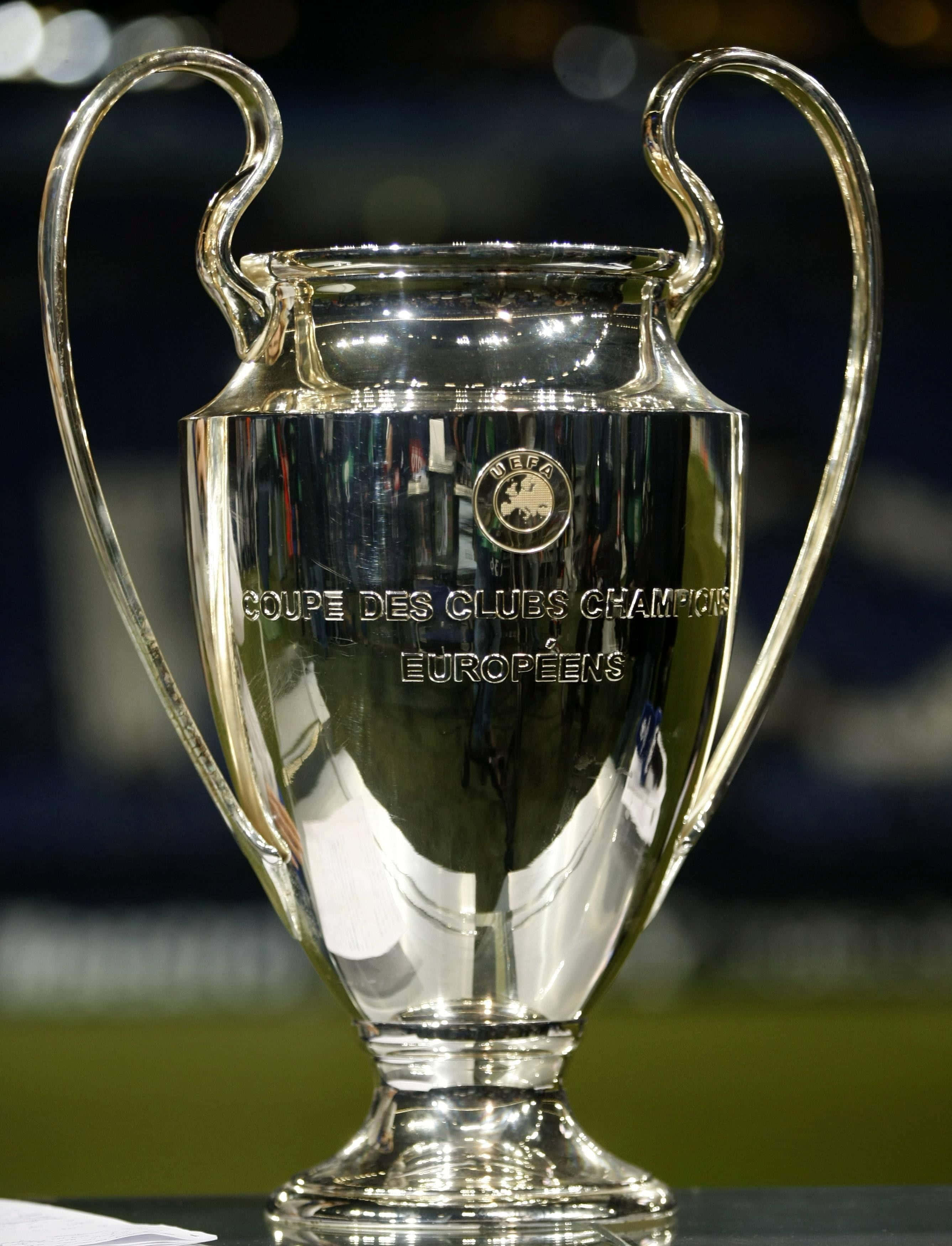Champions League 桌布 壁紙 — 閃亮的銀色歐洲聯賽冠軍盃，帶有彎曲手柄和刻字，反射球場燈光。