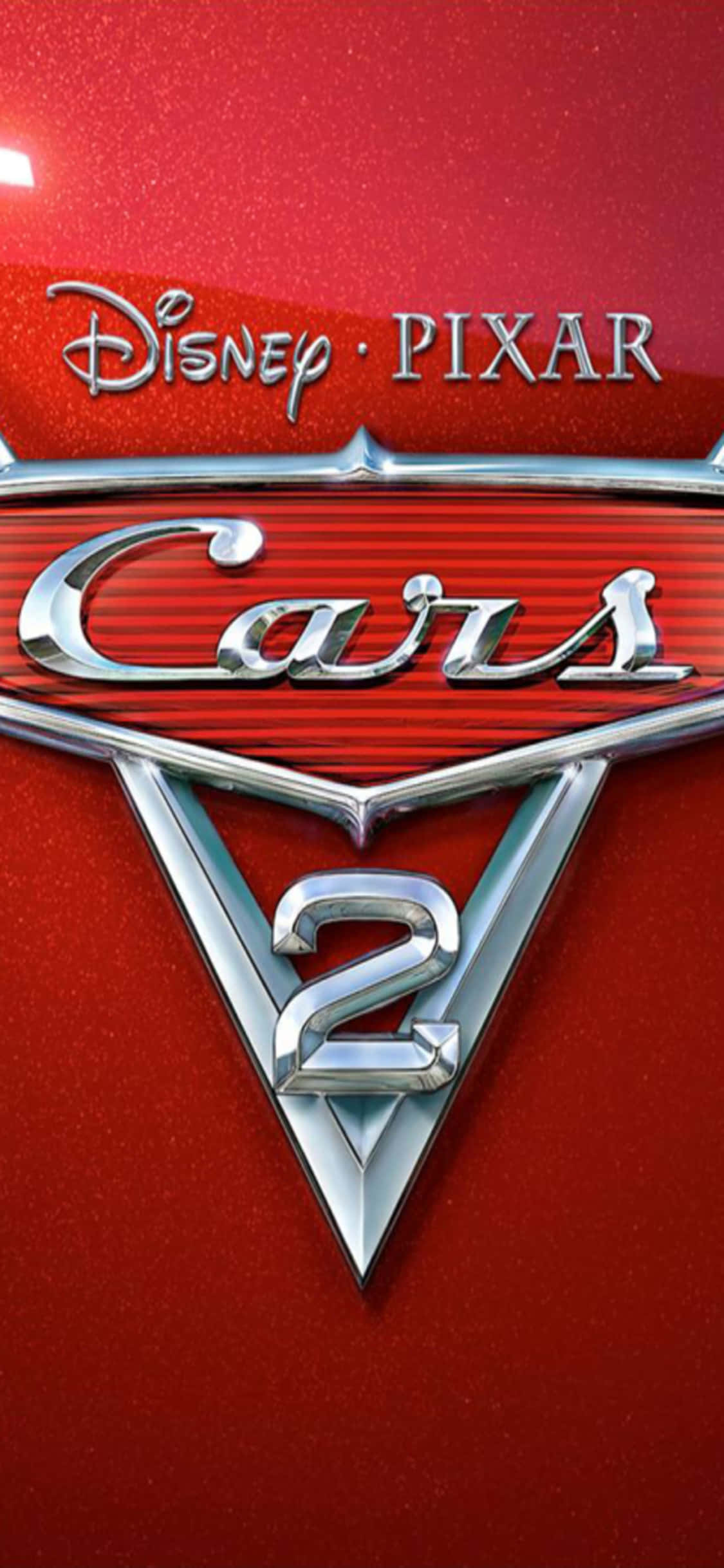 迪士尼 桌布 壁紙 — 閃亮的鍍鉻「Cars 2」標誌在明亮的攝影棚燈光下，在帶有紋理的紅色汽車引擎蓋上閃耀。
