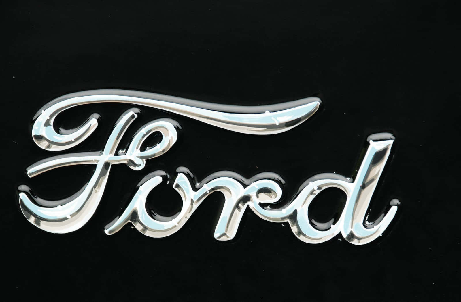 Ford Logo 桌布 壁紙 — 閃亮的鍍鉻福特標誌徽章在純黑背景上閃耀，帶有反射高光。