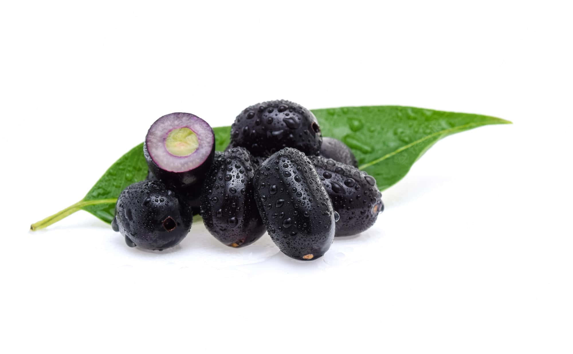 Fruit 桌布 壁紙 — 閃亮的黑色漿果，其中一個切開露出紫色果肉，放在帶露水的綠色葉子上，背景是純白色。
