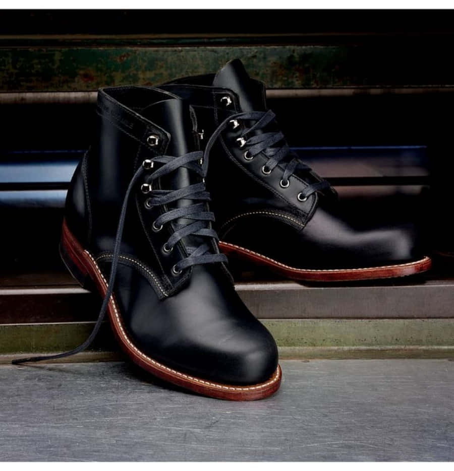 Black Leather 桌布 壁紙 — 閃亮的黑色皮革繫帶靴子搭配棕色鞋底，放置在風化的金屬階梯上，背景為深色鄉村風格。