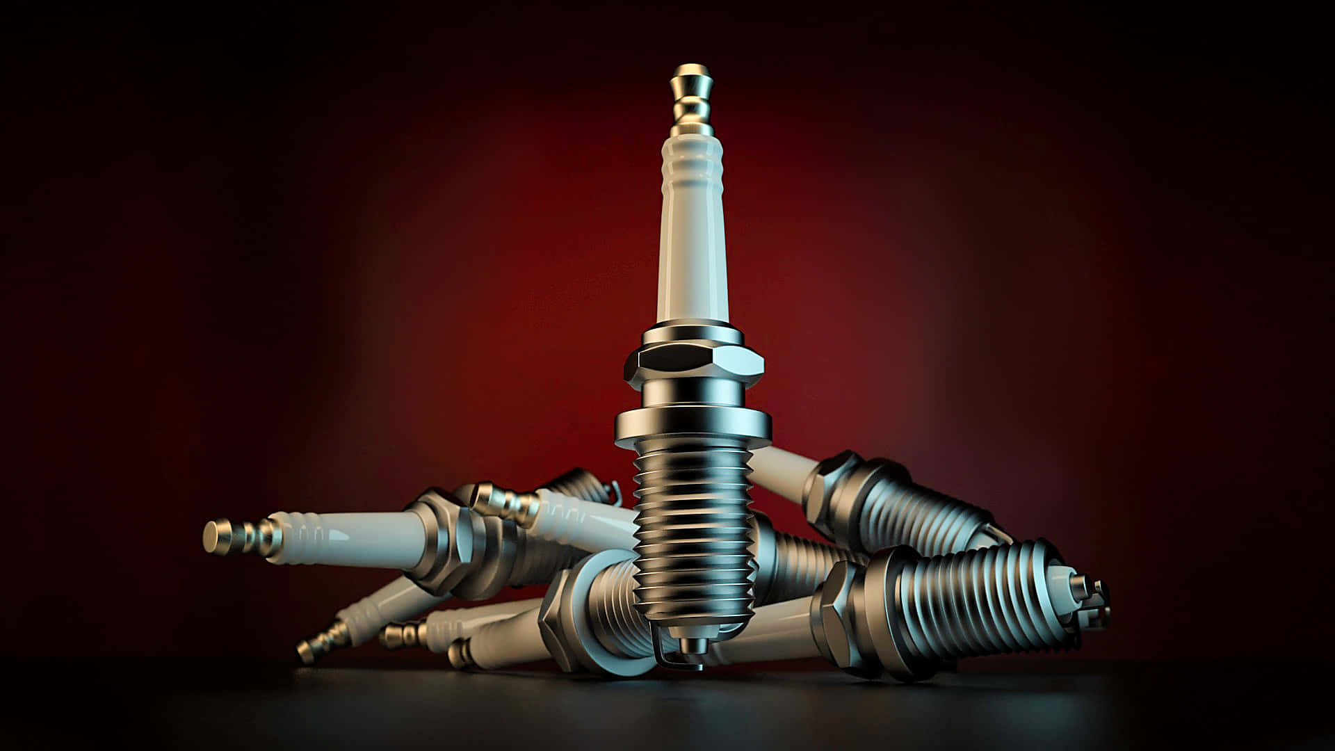 Spark Plug 桌布 壁紙 — 閃亮金屬火星塞堆疊在深紅色漸變背景上，配以戲劇性燈光。