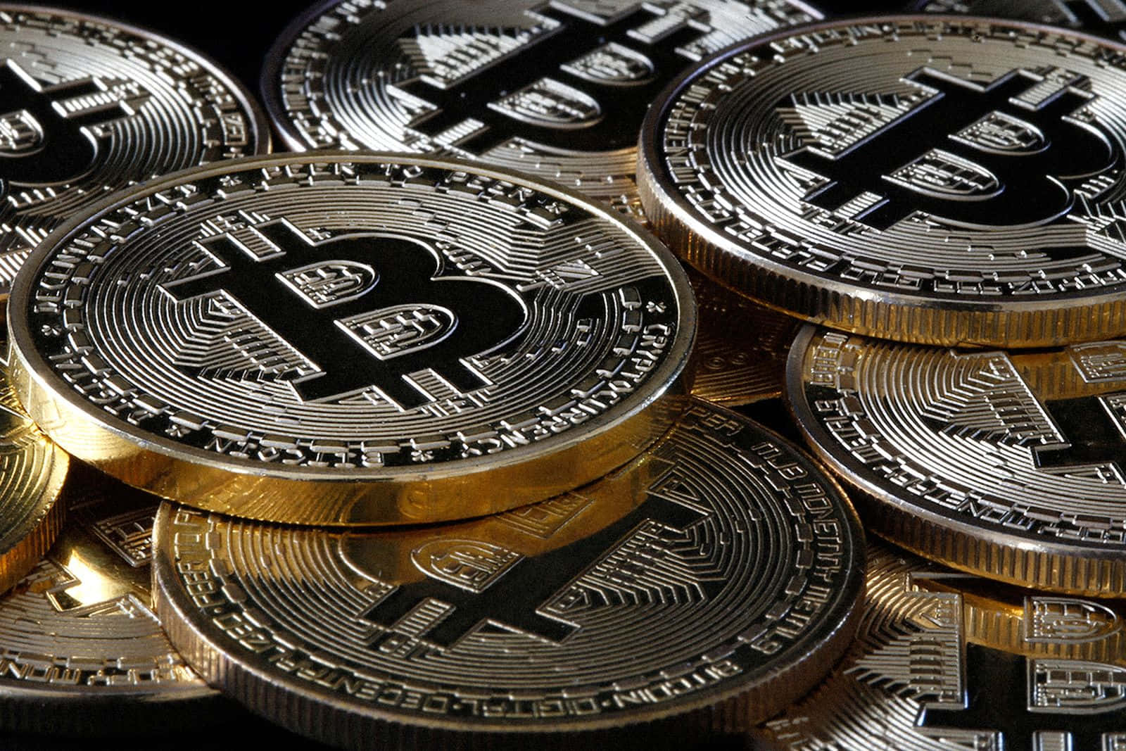 Money 桌布 壁紙 — 閃亮金色和銀色比特幣硬幣的特寫，堆疊重疊，帶有雕刻符號和文字。