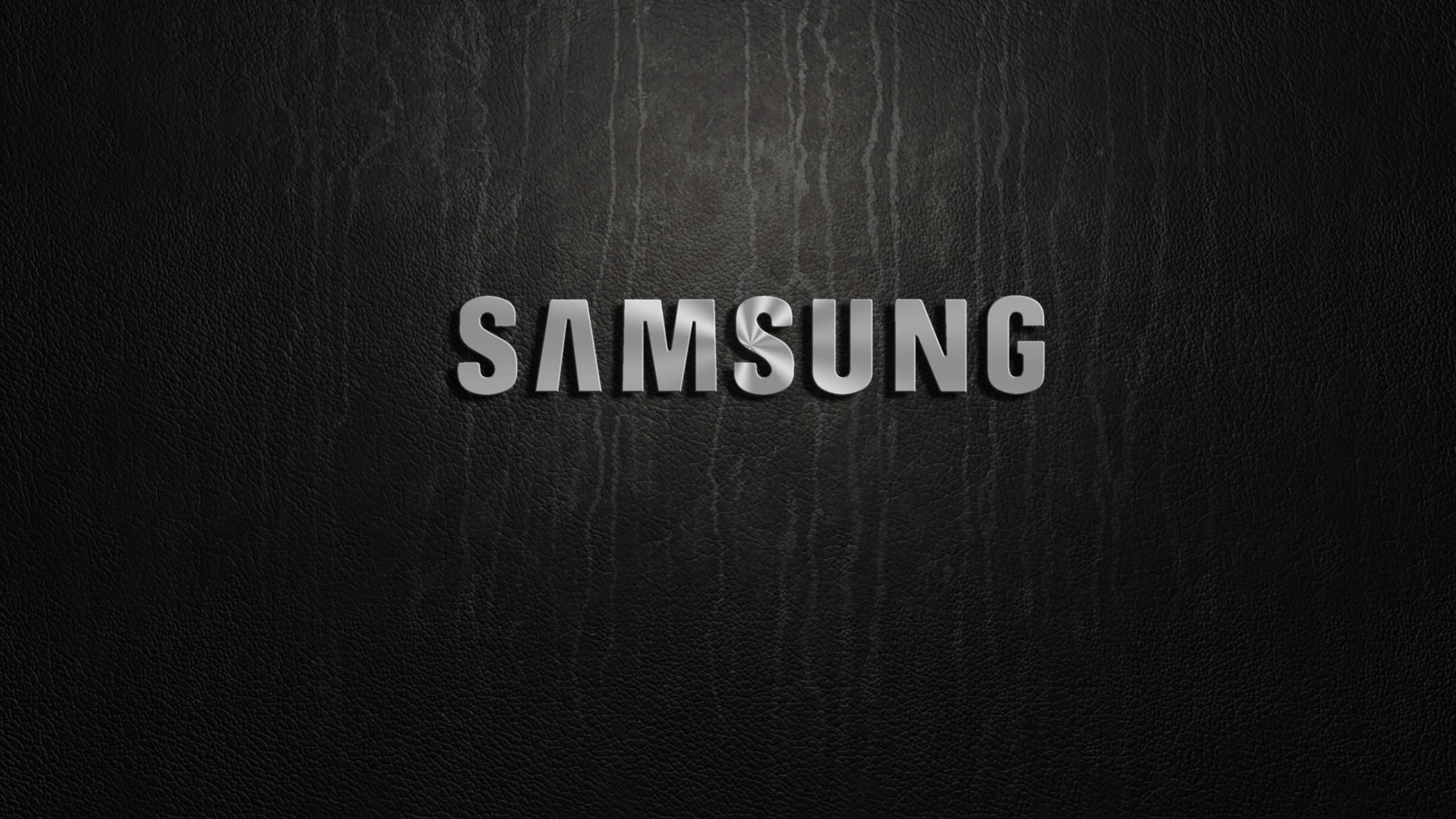 銀色 桌布 壁紙 — 閃亮銀色Samsung標誌居中於帶有細微垂直紋理的黑色皮革背景上。