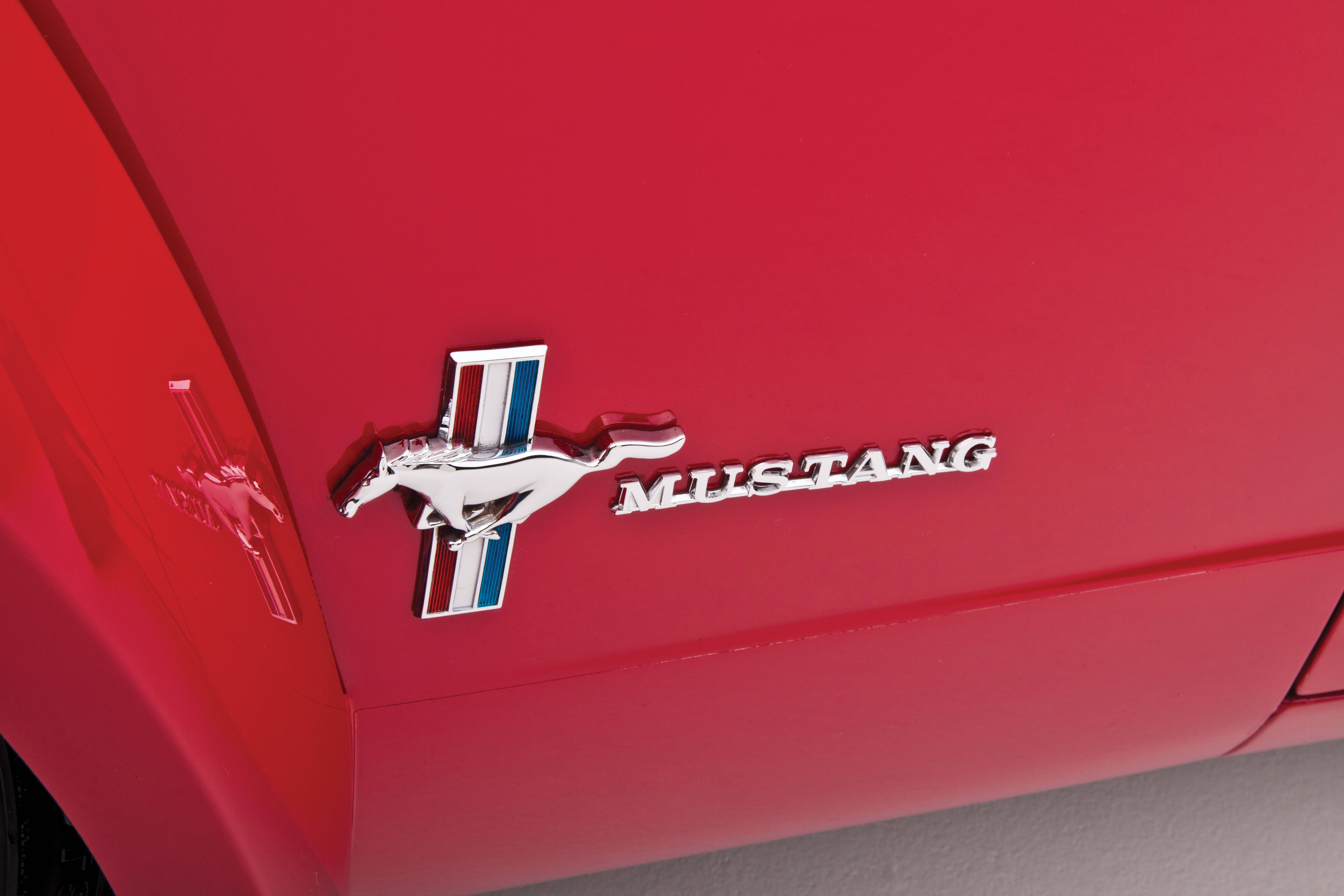 mustang HD 桌布 壁紙 — 閃亮鍍鉻野馬標誌的特寫，位於鮮紅色汽車引擎蓋上，表面反光。