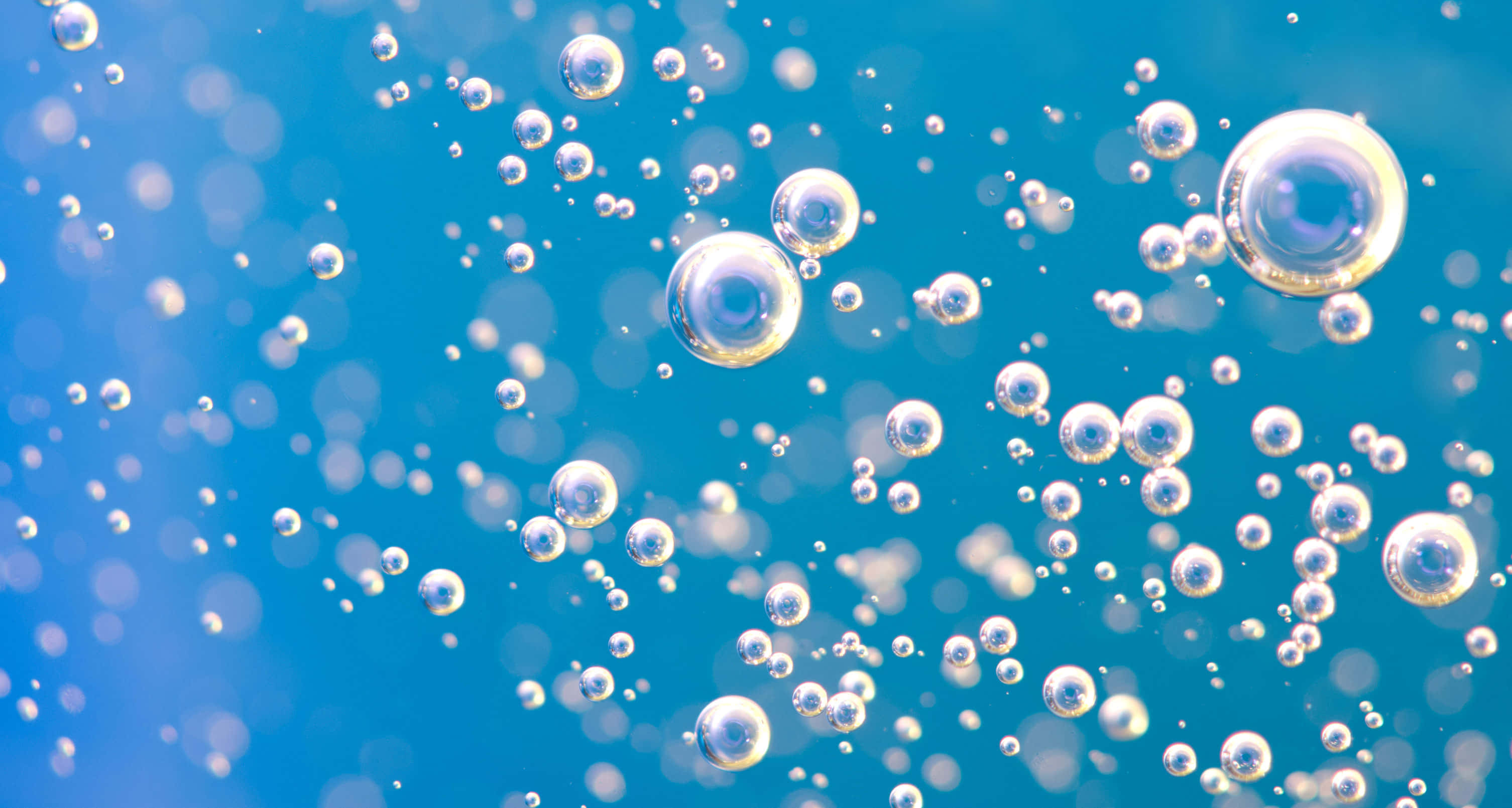 Bubble 桌布 壁紙 — 閃爍的氣泡在充滿活力的藍色漸變背景上優雅地漂浮，帶有柔和的散景效果。