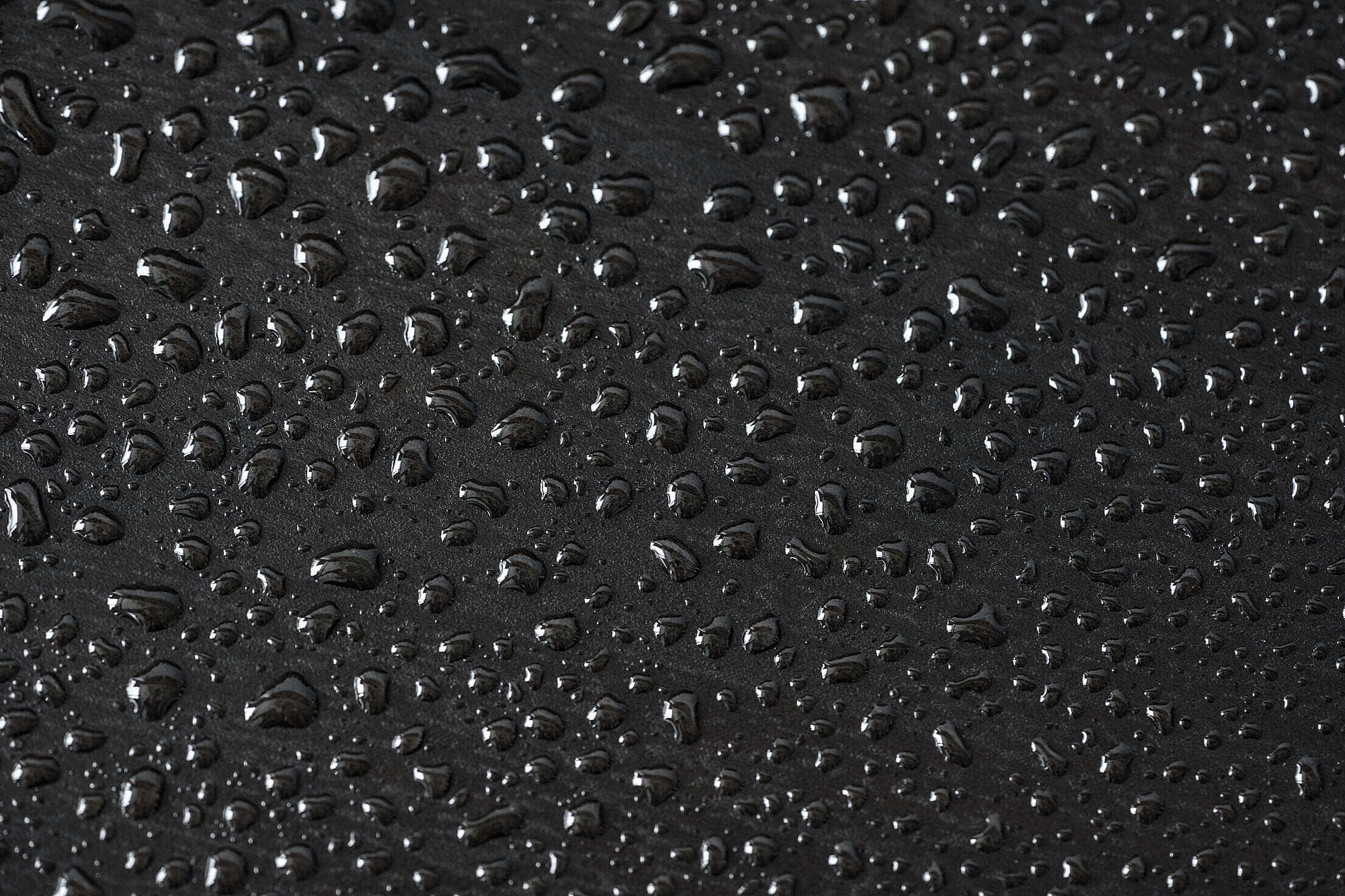 Black Pattern 桌布 壁紙 — 閃爍的水滴依附在啞光黑色表面上，營造出光滑的反射質感。