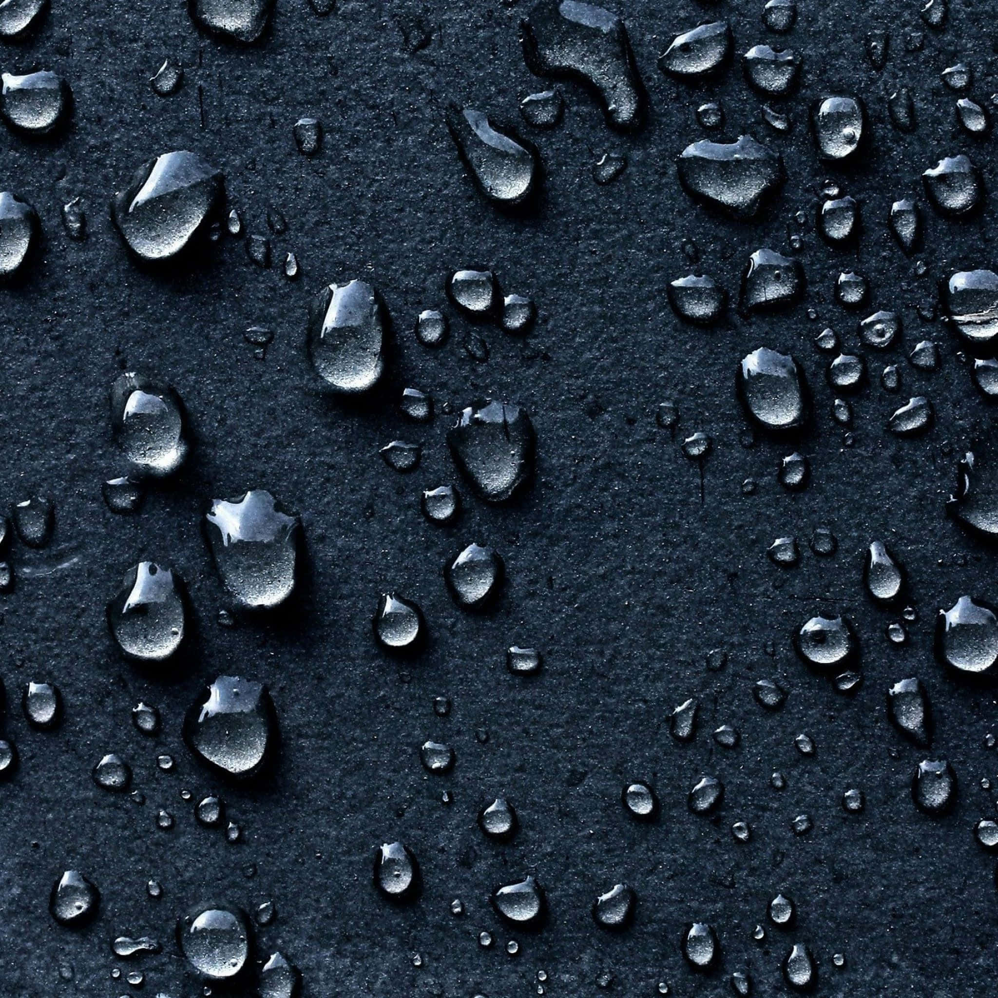 Water iPad 桌布 壁紙 — 閃爍的水滴停留在霧面黑色紋理表面上，反射柔和環境光。