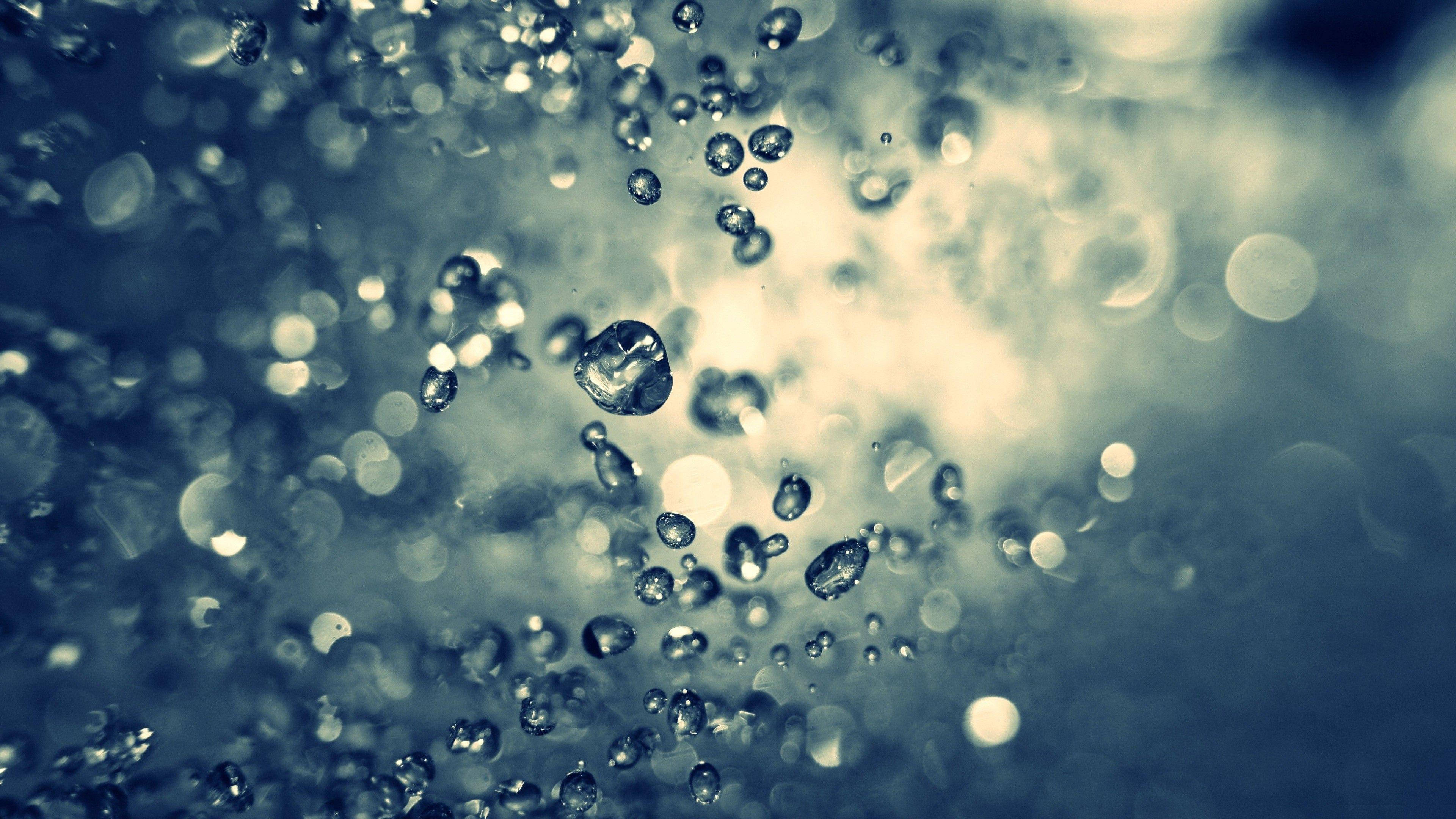 水 桌布 壁紙 — 閃爍的水滴在柔和的模糊背景中懸浮移動，帶有清涼的藍色和奶油色調。