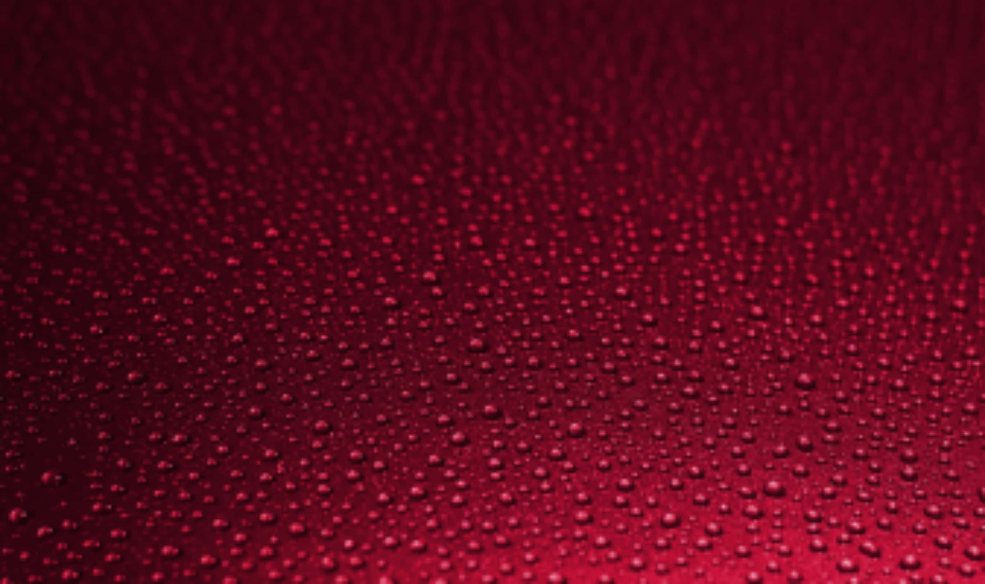 Droplets 桌布 壁紙 — 閃爍的水滴散佈在豐富的漸變紅色表面上，形成紋理化的抽象圖案。