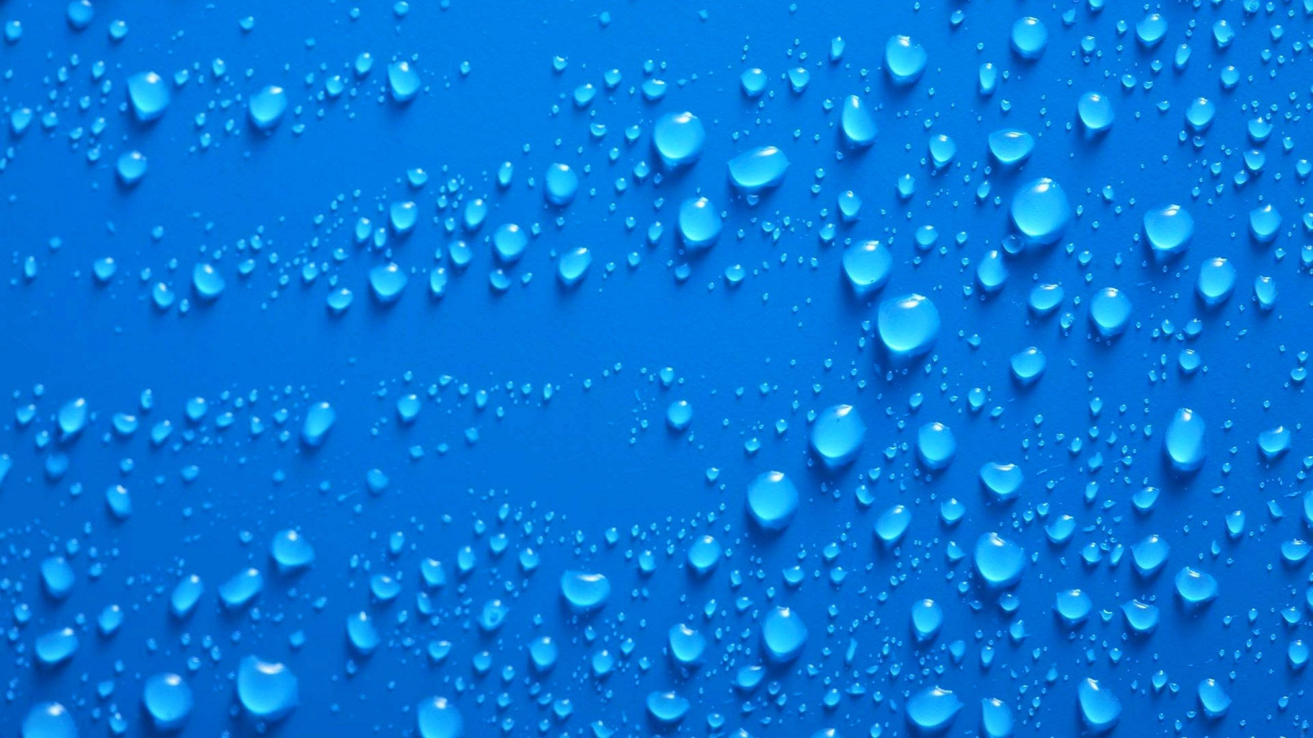 水 桌布 壁紙 — 閃爍的水滴散佈在鮮豔的藍色表面上，營造出清涼清爽的抽象紋理。