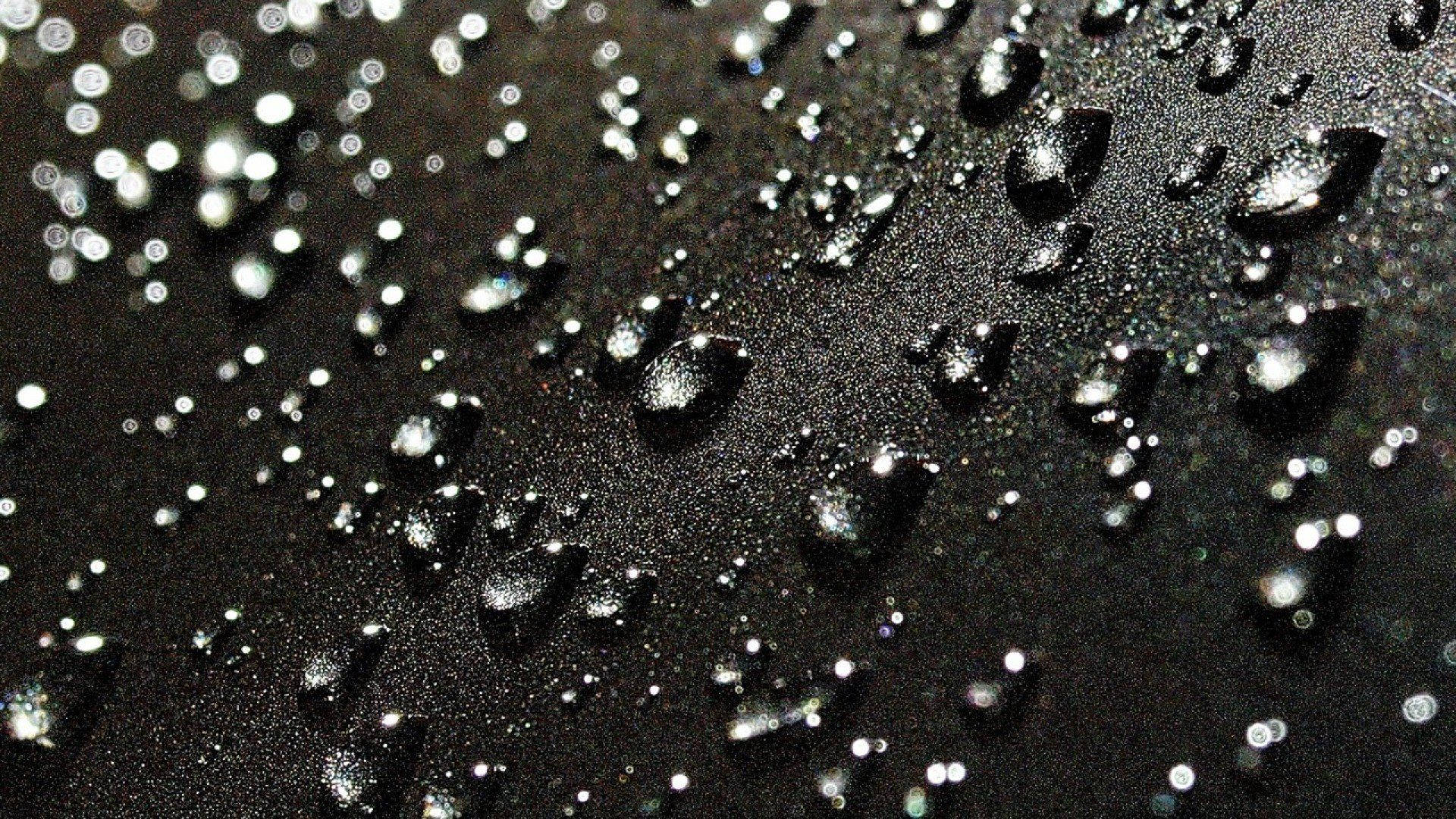Rainy Day 桌布 壁紙 — 閃爍的水滴散落在深色紋理表面上，捕捉光線，形成閃閃發光的抽象圖案。