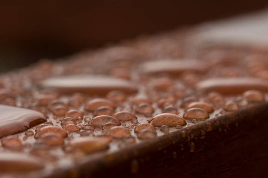 Droplets 桌布 壁紙 — 閃爍的水珠停留在帶有紋理的木質表面上，呈現溫暖的棕色調，景深較淺。