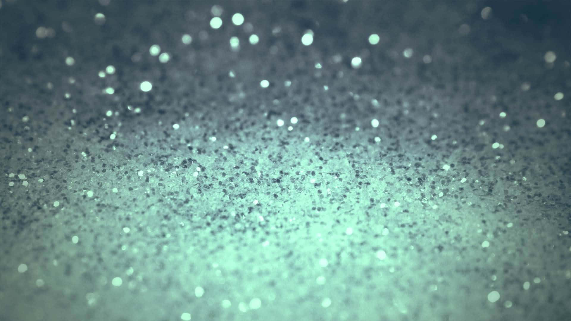 White Glitter 桌布 壁紙 — 閃爍的藍綠色亮粉顆粒散落在深色紋理表面上的特寫，帶有柔和散景高光。