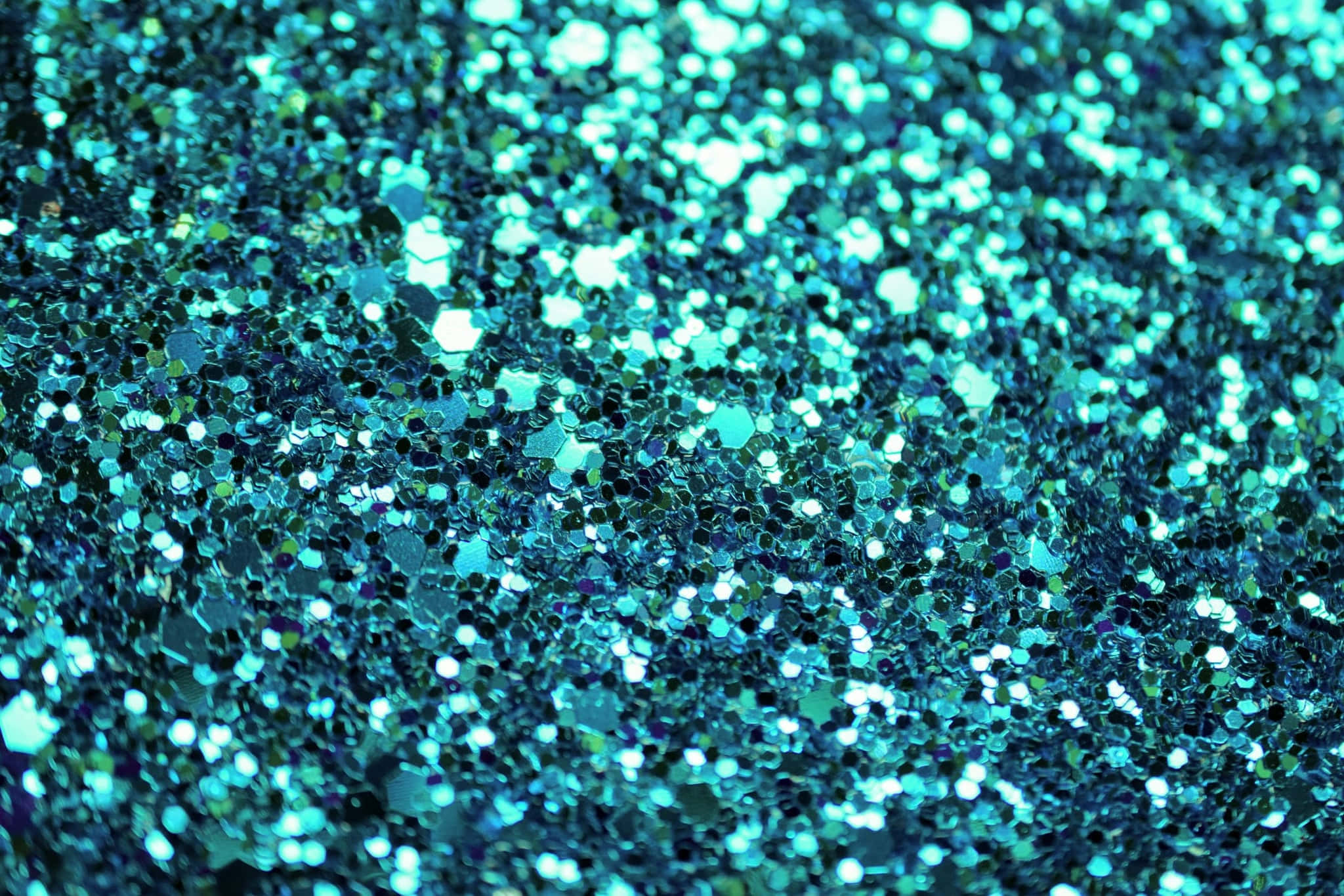 Glittery 桌布 壁紙 — 閃爍的藍綠色和藍色亮粉顆粒在光線下形成閃亮質感的特寫。