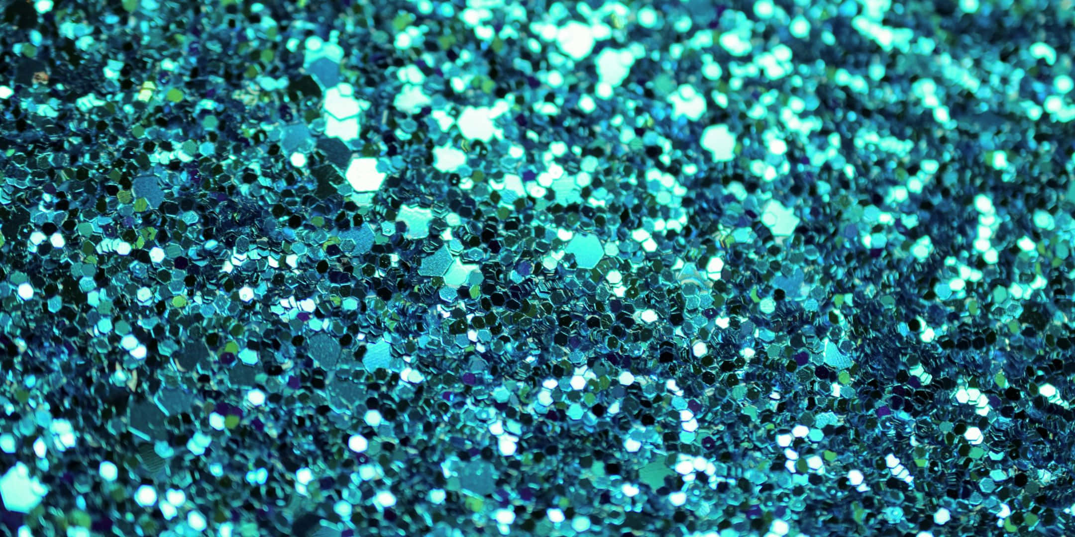 Teal Glitter 桌布 壁紙 — 閃爍的藍綠色和藍色亮粉顆粒在密集、閃亮的紋理中捕捉光線的特寫。