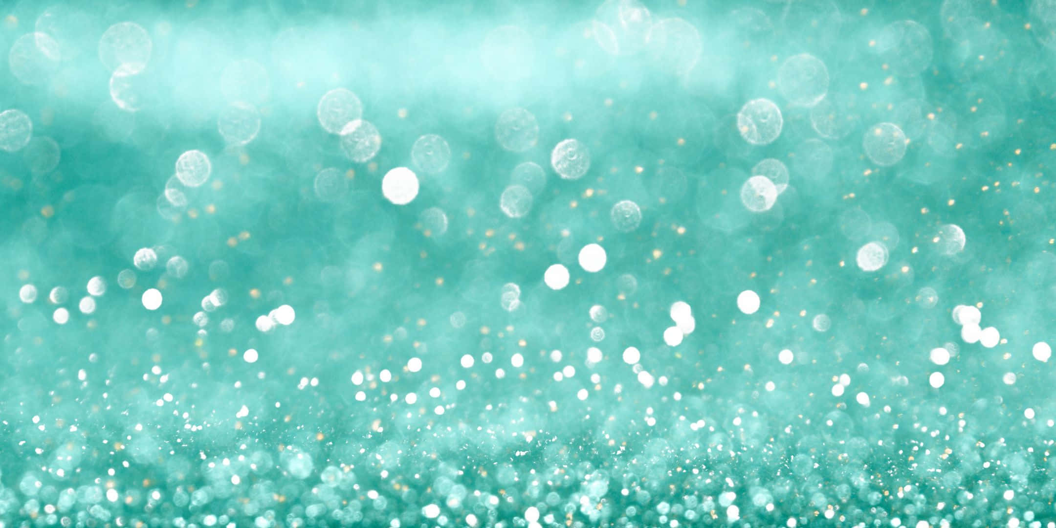 Teal Glitter 桌布 壁紙 — 閃爍的藍綠色背景，帶有柔和散景燈光和閃亮粒子，營造夢幻節日氣氛。
