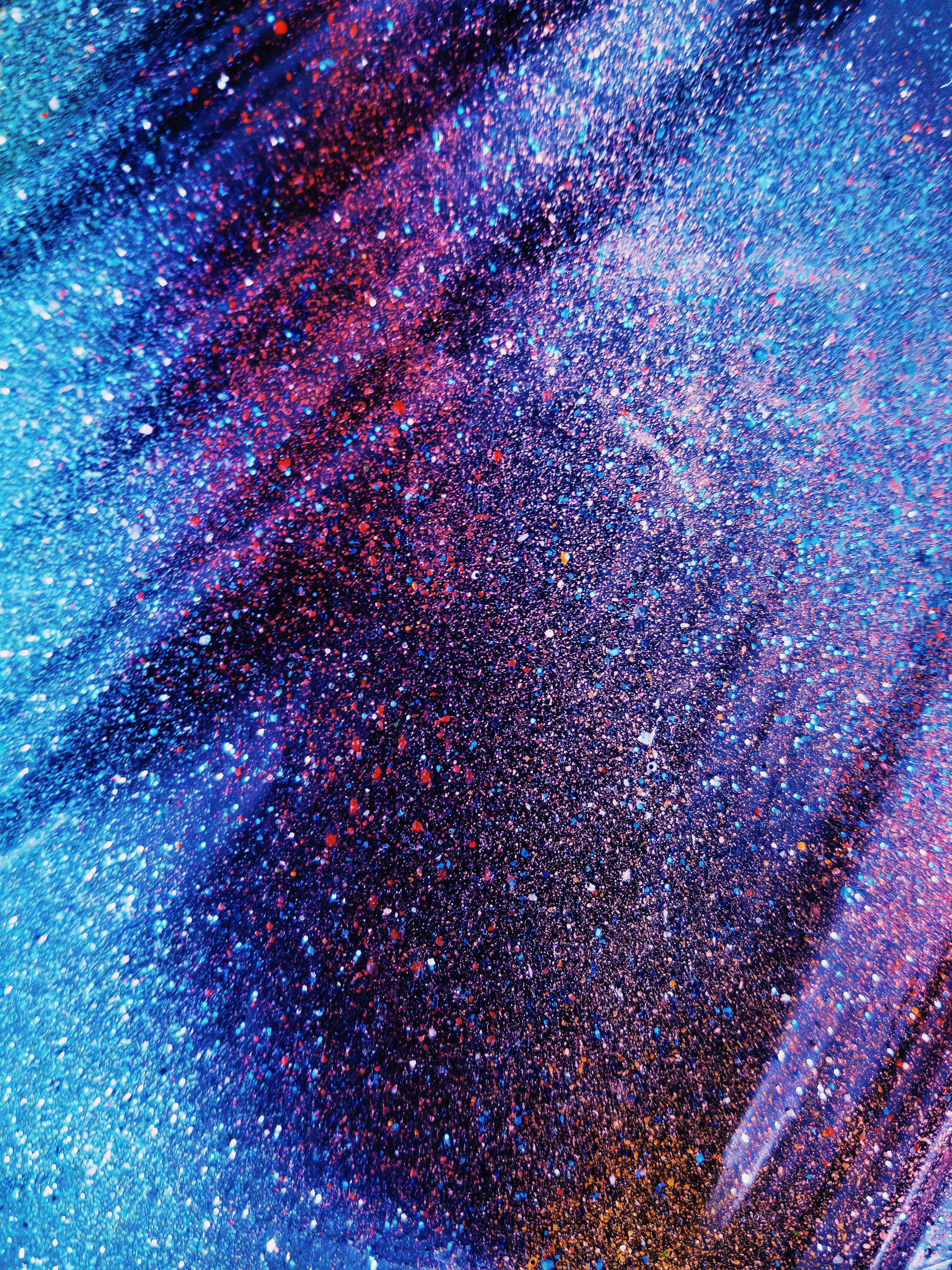 酷炫美學 桌布 壁紙 — 閃爍的藍色、紫色和紅色粒子形成宇宙漩渦，營造出夢幻的銀河效果。
