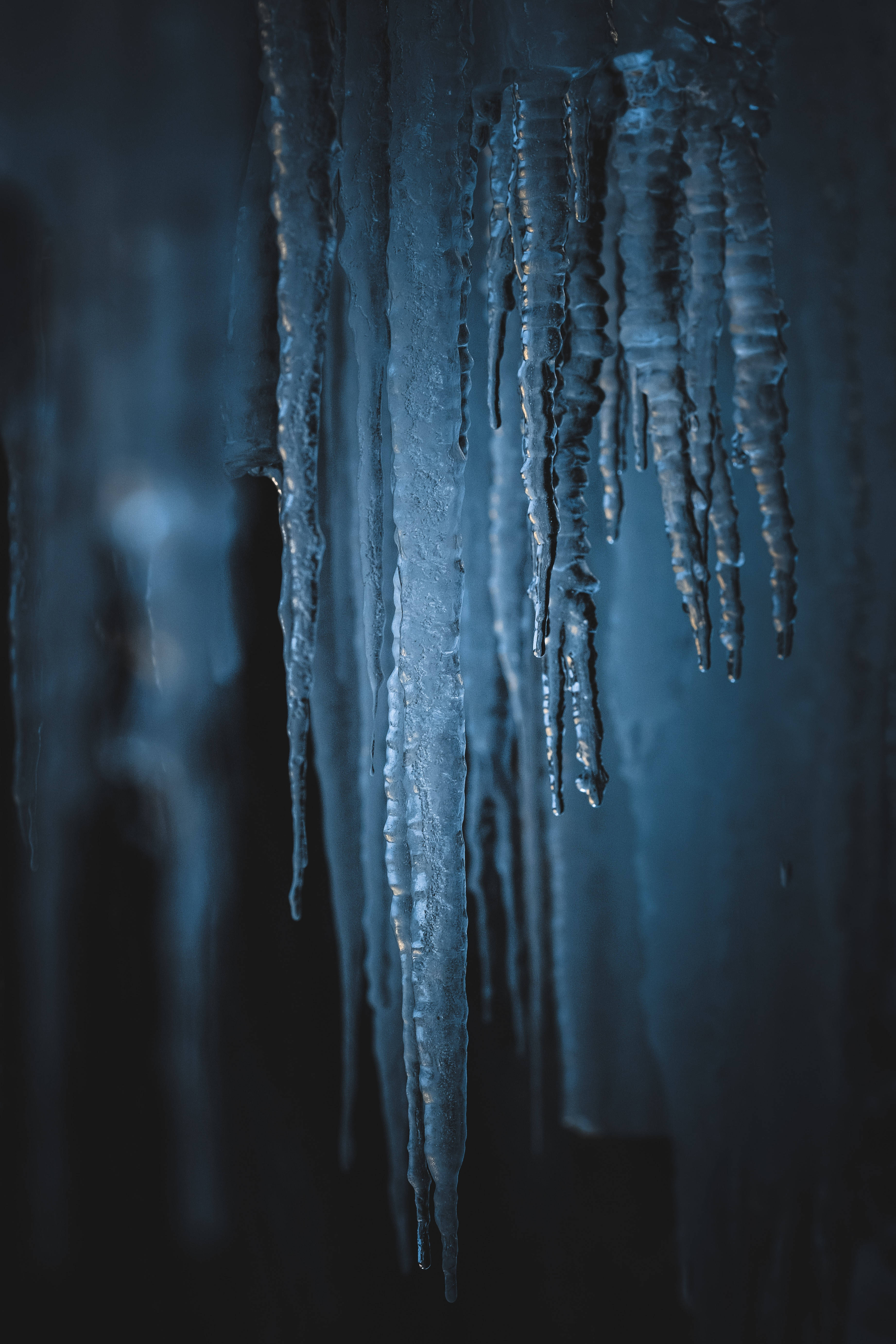 冰雪奇緣 桌布 壁紙 — 閃爍的藍色冰柱懸掛在黑暗的洞穴中，由清涼的環境光照亮，展現出複雜的冰凍紋理。
