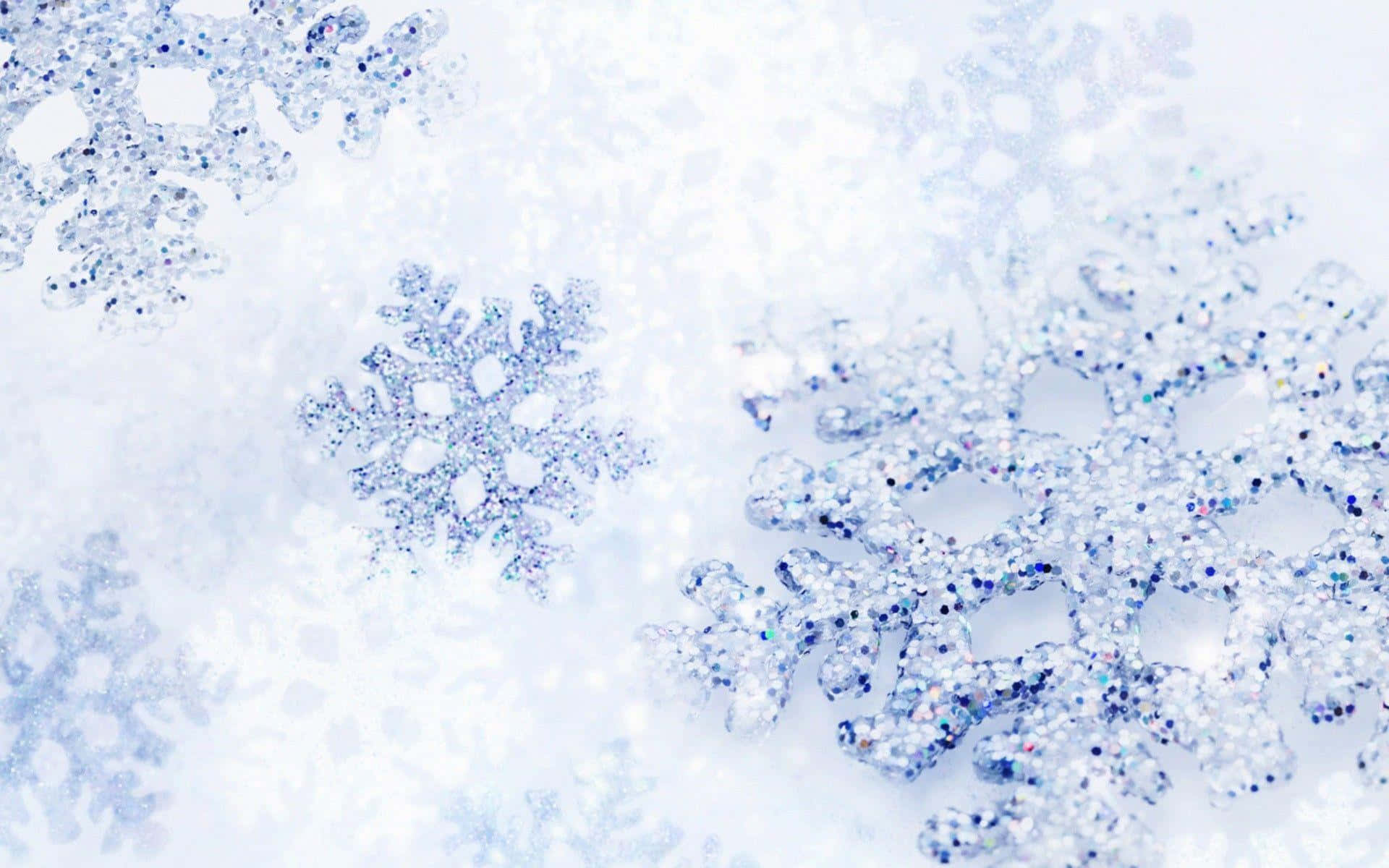 Snowy Christmas 桌布 壁紙 — 閃爍的藍色和白色雪花，帶有閃閃發光的亮片細節，停留在柔軟的雪地上。