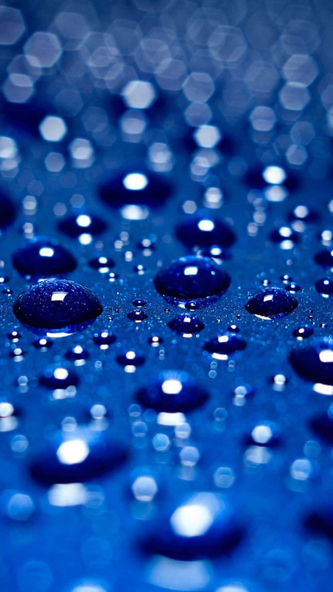 Water Droplet 桌布 壁紙 — 閃爍的藍色水滴停留在表面上，背景中六角形的散景燈光柔和地發光。