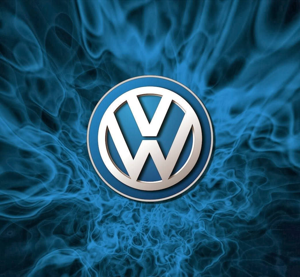福斯汽車 桌布 壁紙 — 閃爍的藍色煙霧圍繞著畫面中央的金屬質感 Volkswagen 標誌旋轉。