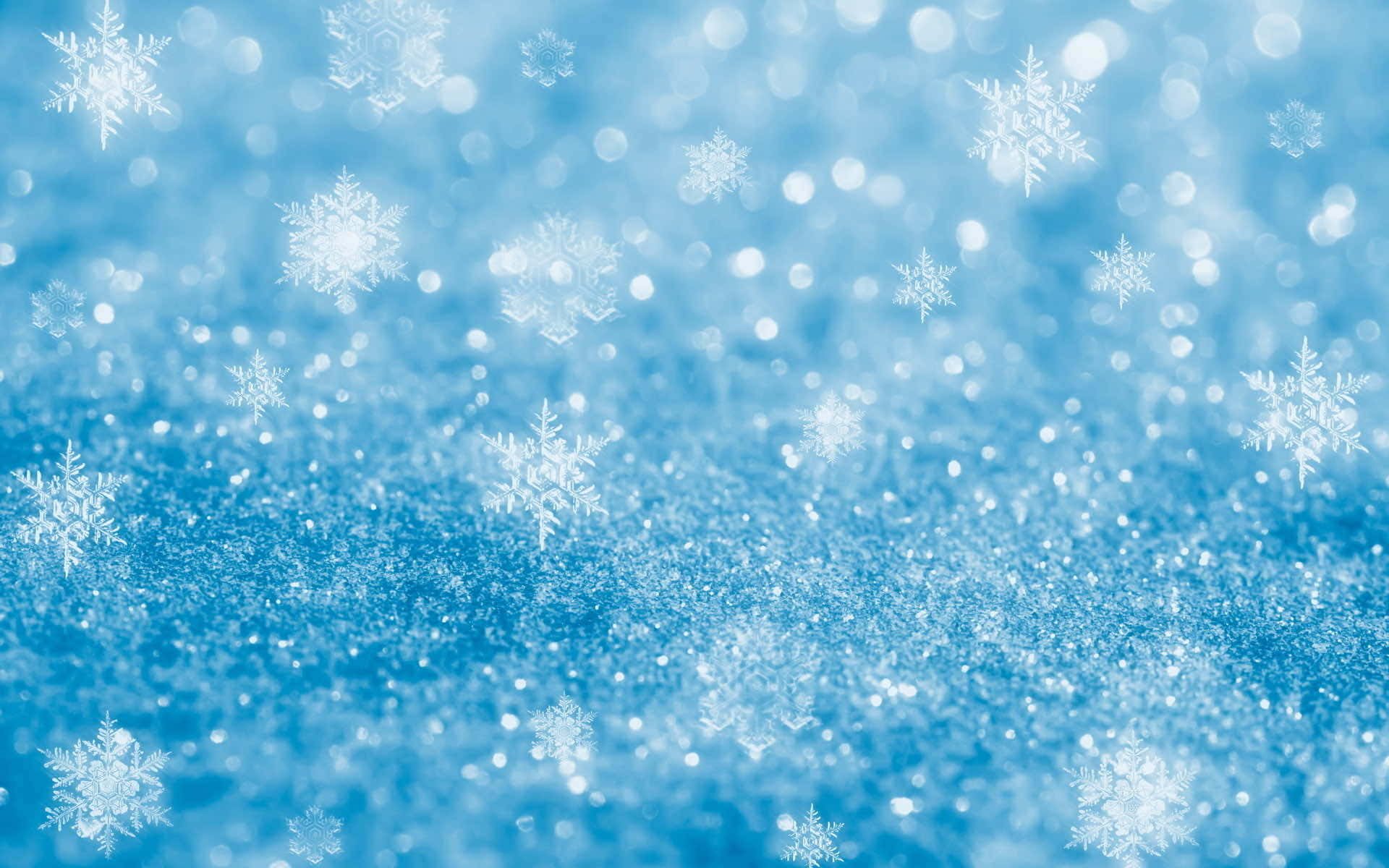 Snowflakes 桌布 壁紙 — 閃爍的藍色背景，帶有精緻的白色雪花和散景燈光，營造出節日的冬季仙境。