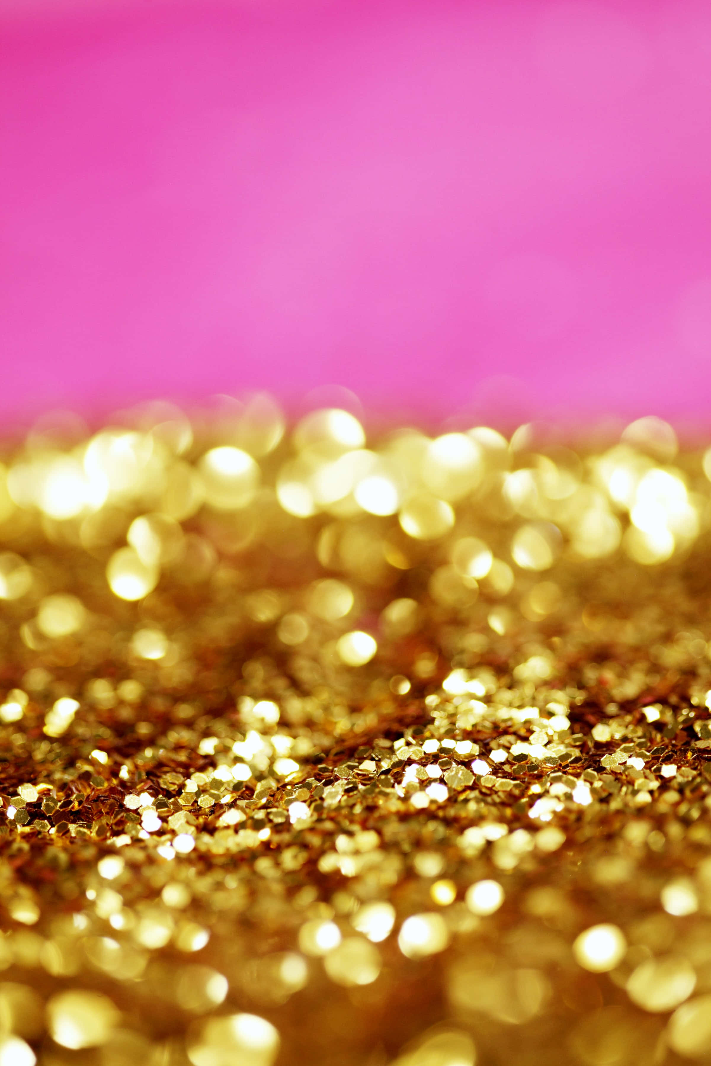 Gold Glitter 桌布 壁紙 — 閃爍的金色亮粉在淺景深下，映襯著充滿活力的粉紅色背景。