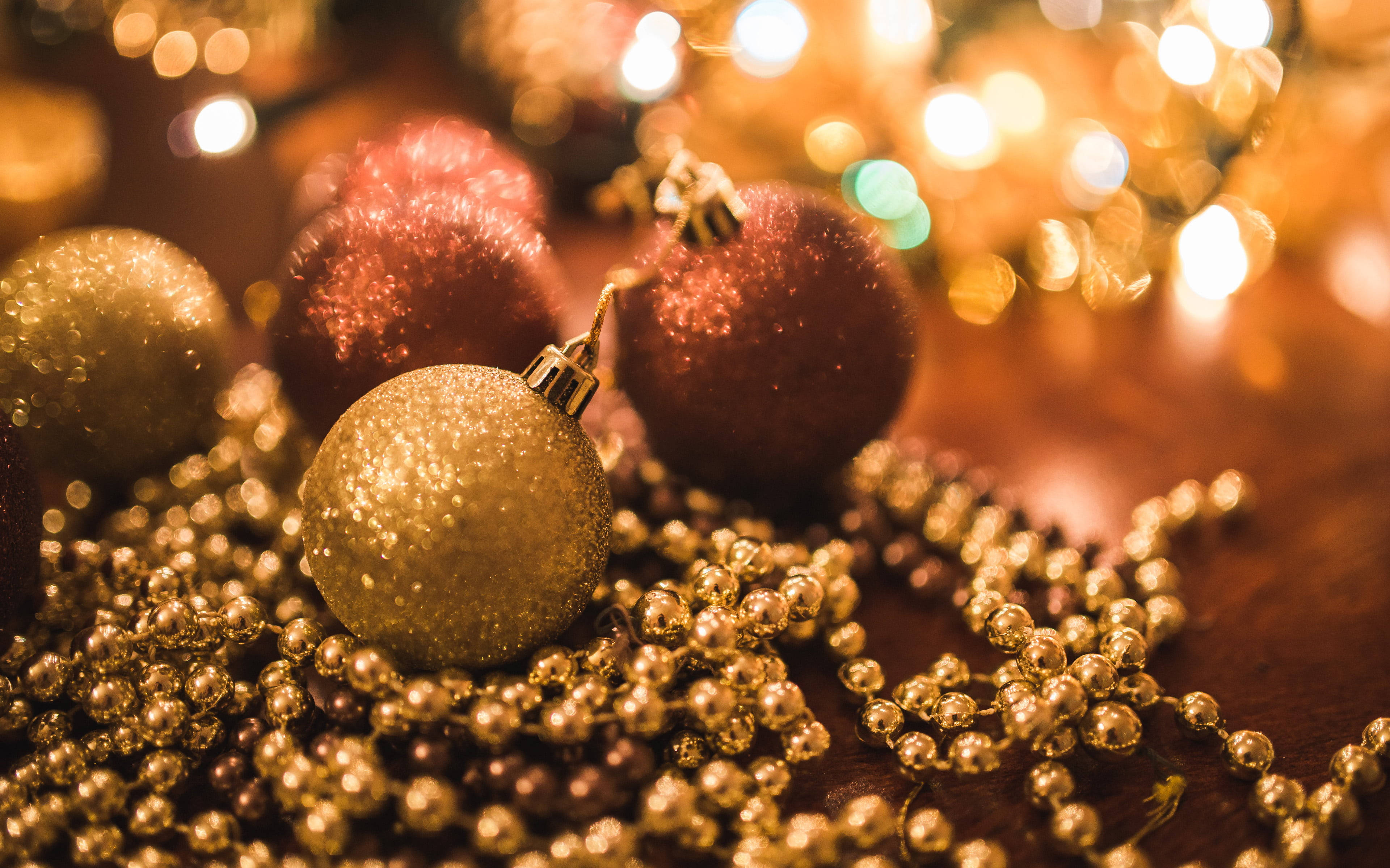 balls 桌布 壁紙 — 閃爍的金色和紅色聖誕裝飾品藏在金色珠子之間，背景有溫暖的散景燈光。
