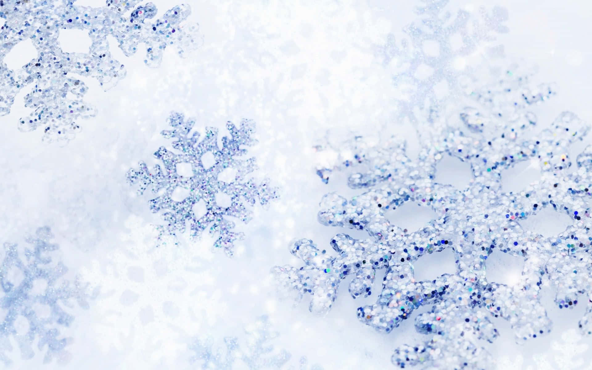  壁紙 — 閃爍的雪花帶有閃閃發光的藍色和銀色斑點，靜靜地躺在柔軟的白色雪面上。