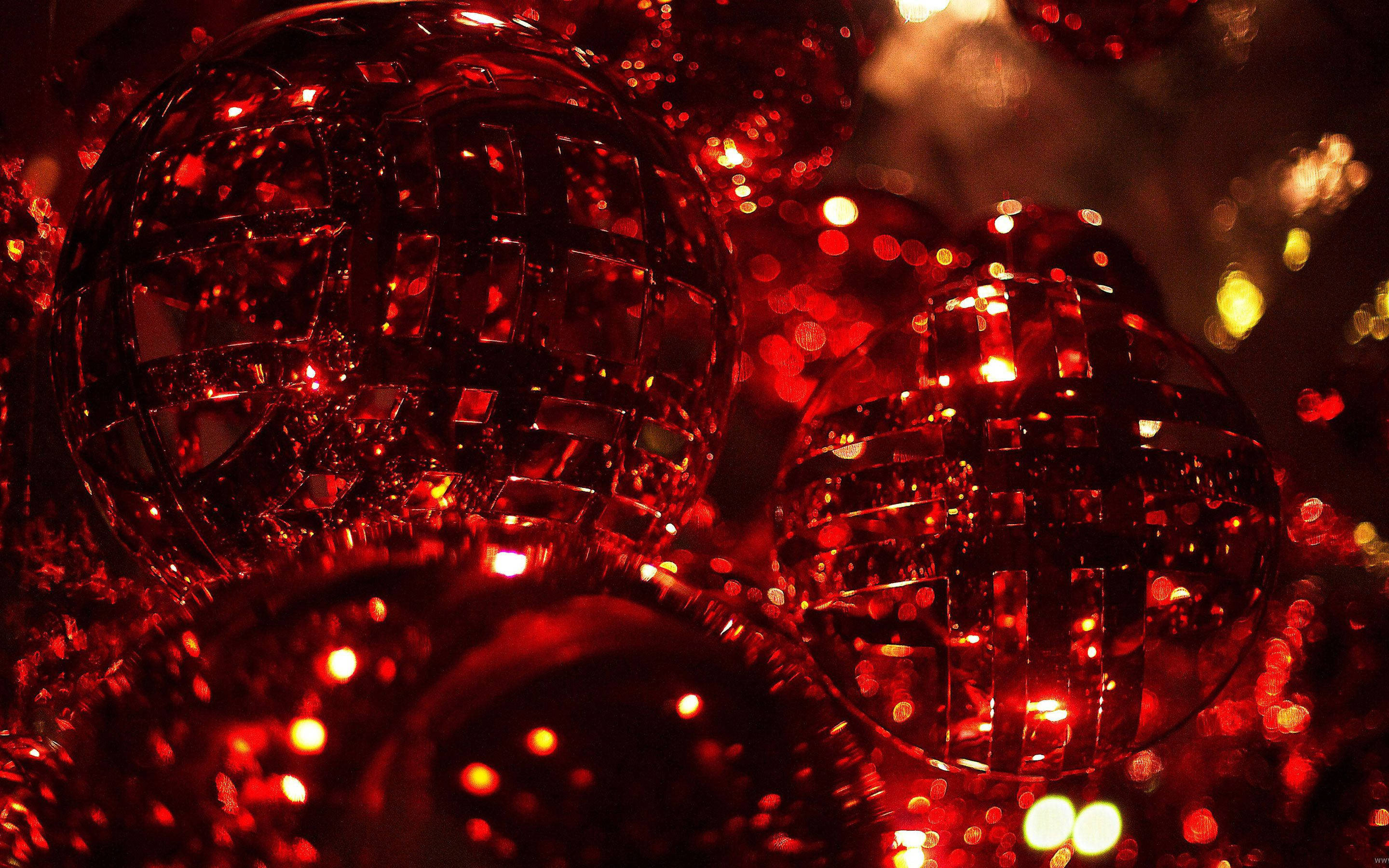 Christmas Balls 桌布 壁紙 — 閃爍紅色迪斯科球的特寫，在黑暗的節日背景下反射溫暖的燈光。