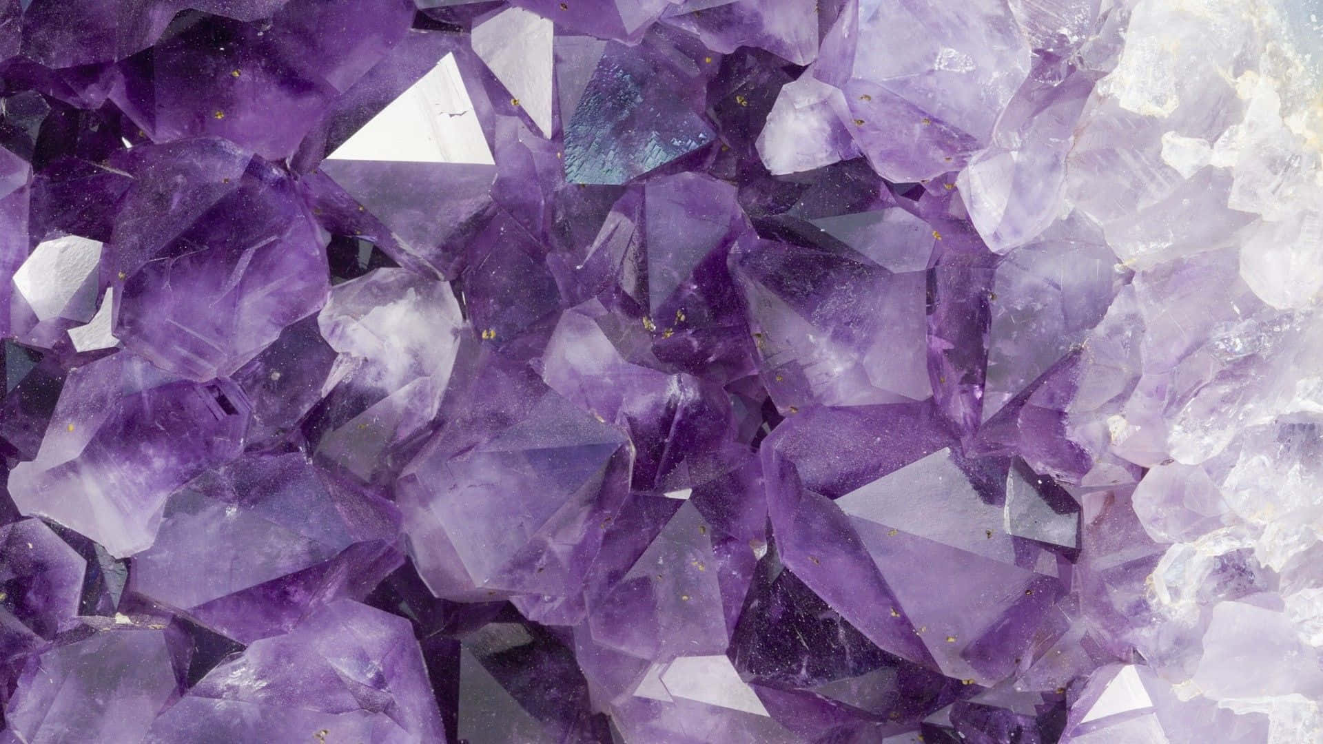 紫水晶 桌布 壁紙 — 閃爍紫水晶晶體的近距離特寫，深紫色和半透明的切面捕捉光線。