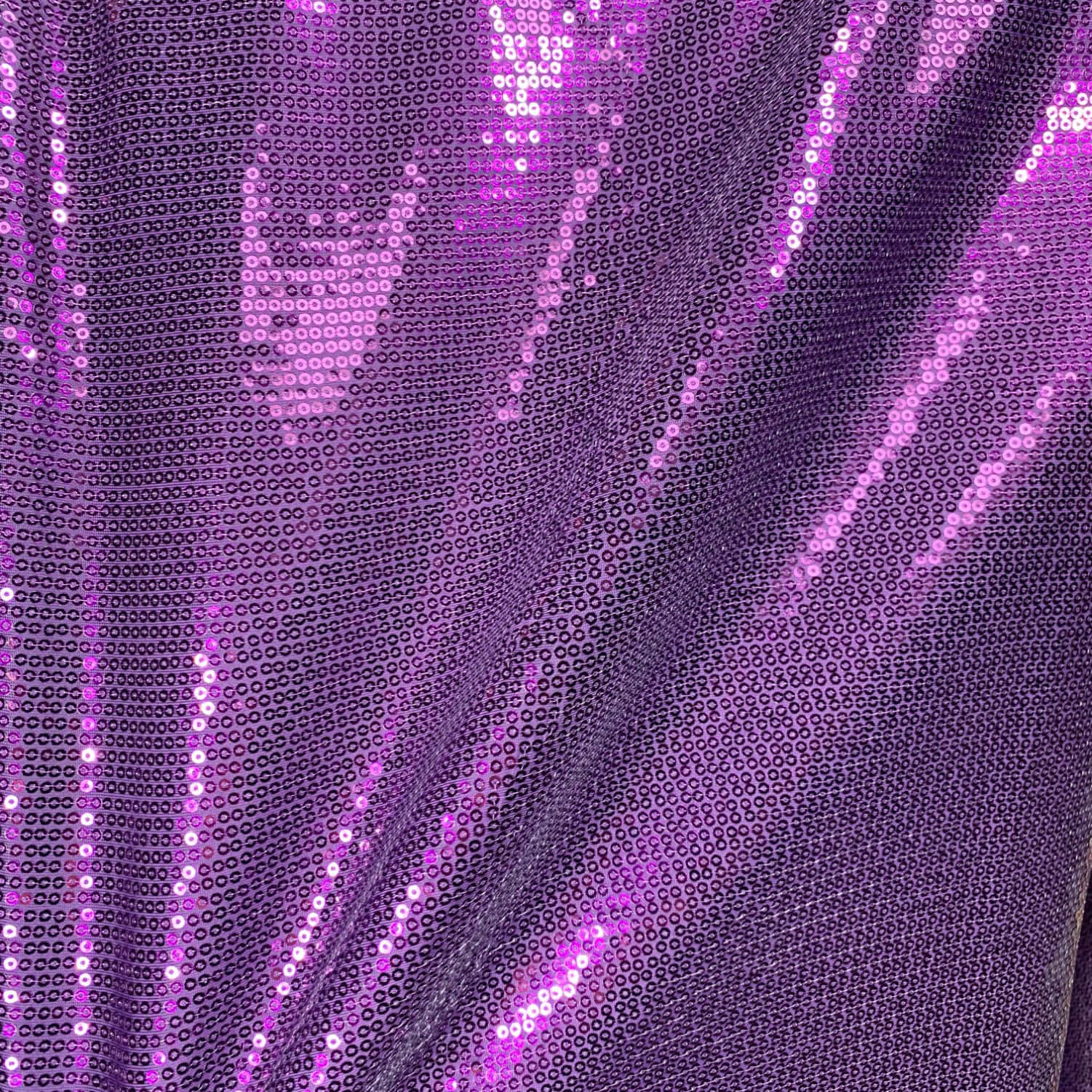 Purple Sequins 桌布 壁紙 — 閃爍紫色亮片布料的特寫，光線在其光澤表面反射，形成鮮豔的高光。