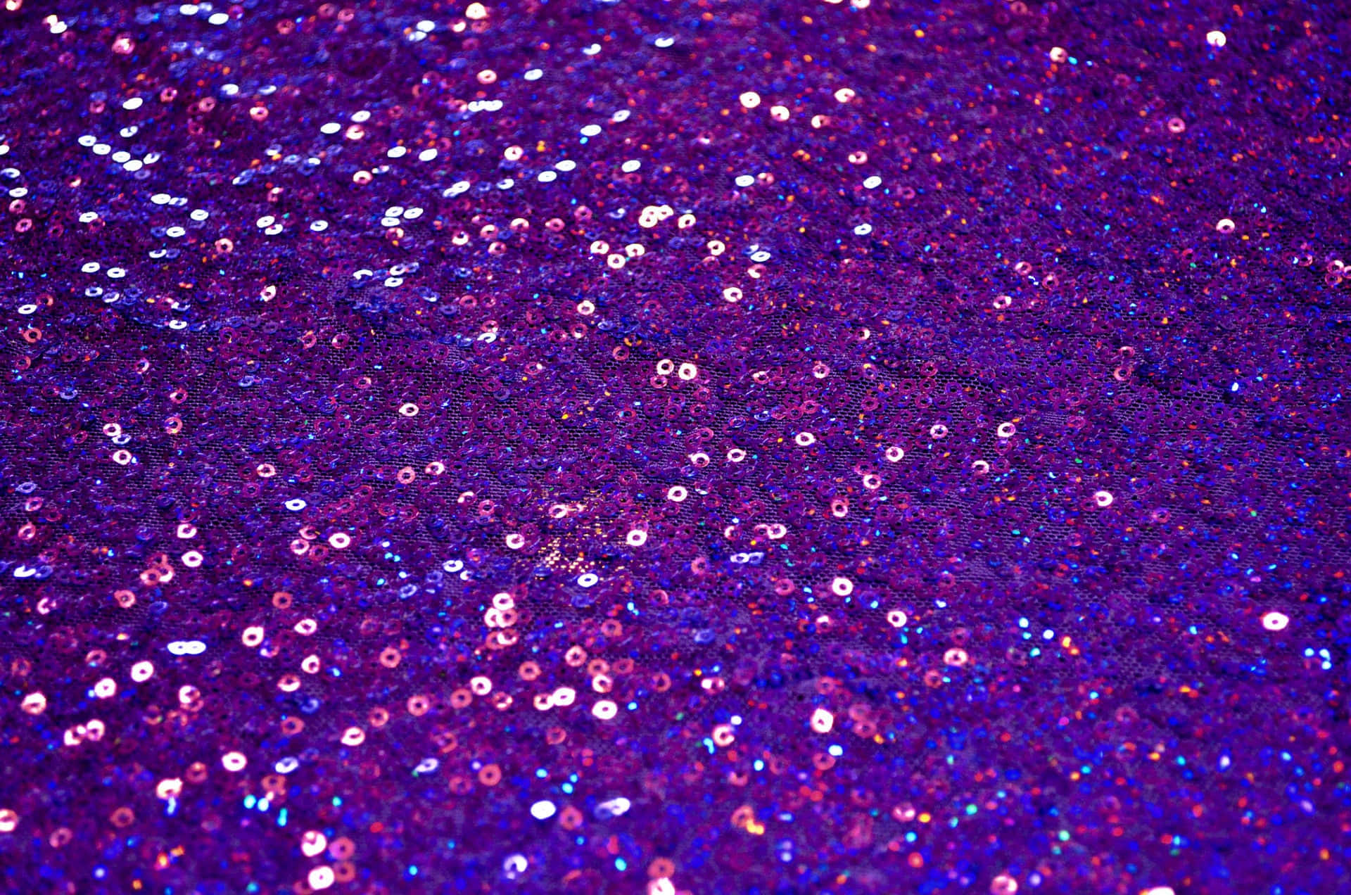 Purple Sequins 桌布 壁紙 — 閃爍紫色和粉紅色亮片在紋理布料表面捕捉光線的特寫。