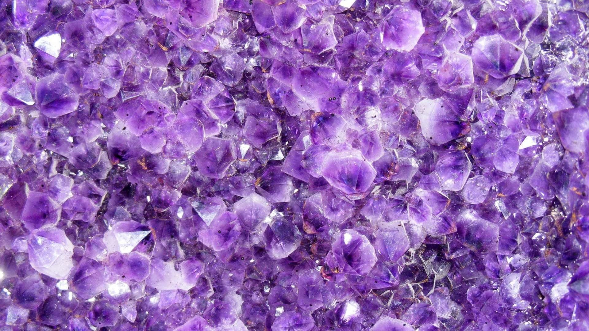 crystals 桌布 壁紙 — 閃爍紫色紫水晶晶體的近距離特寫，形成密集閃亮的簇狀，帶有銳利的刻面和深紫羅蘭色調。